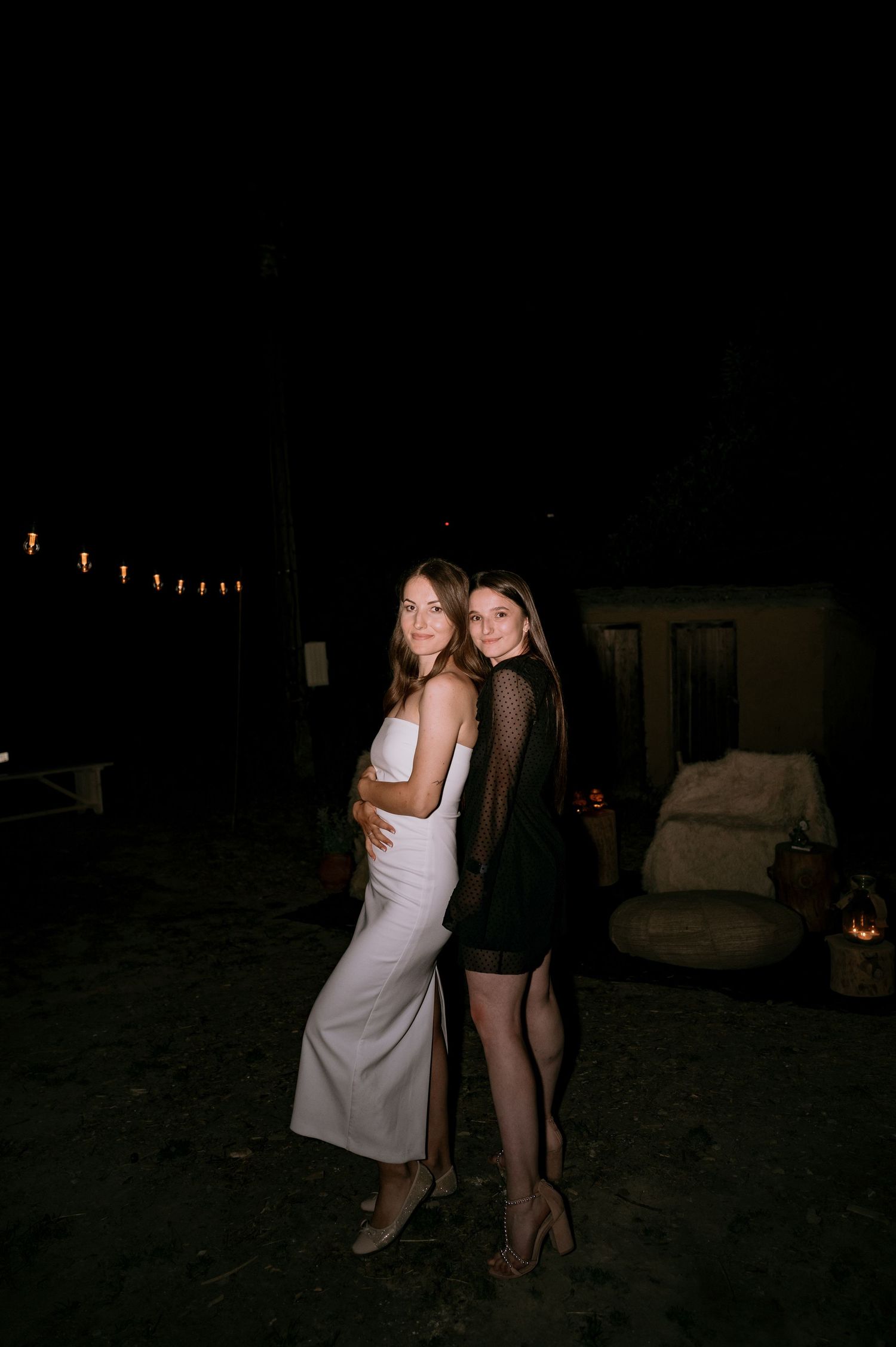 Nighttime outdoor party scene with string lights and guests dancing.