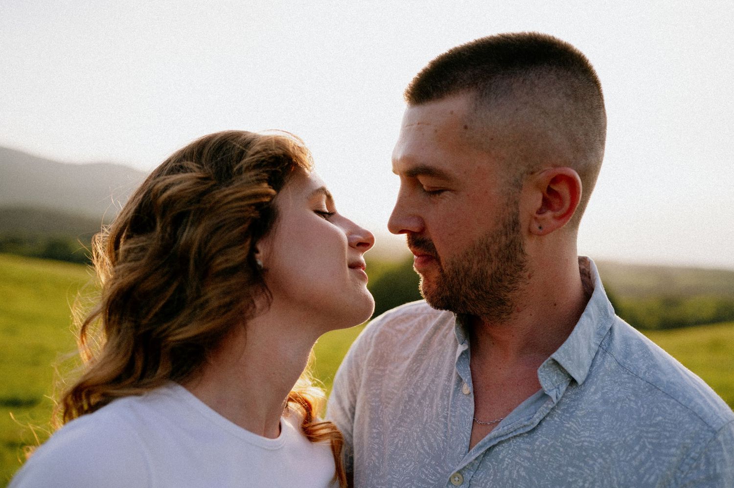 Intimate portrait of couple about to kiss in natural outdoor setting.
