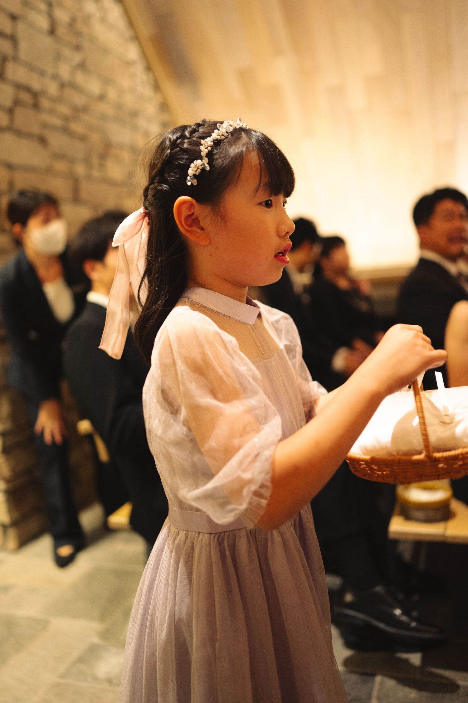Young flower girl in white and grey dress at wedding reception.