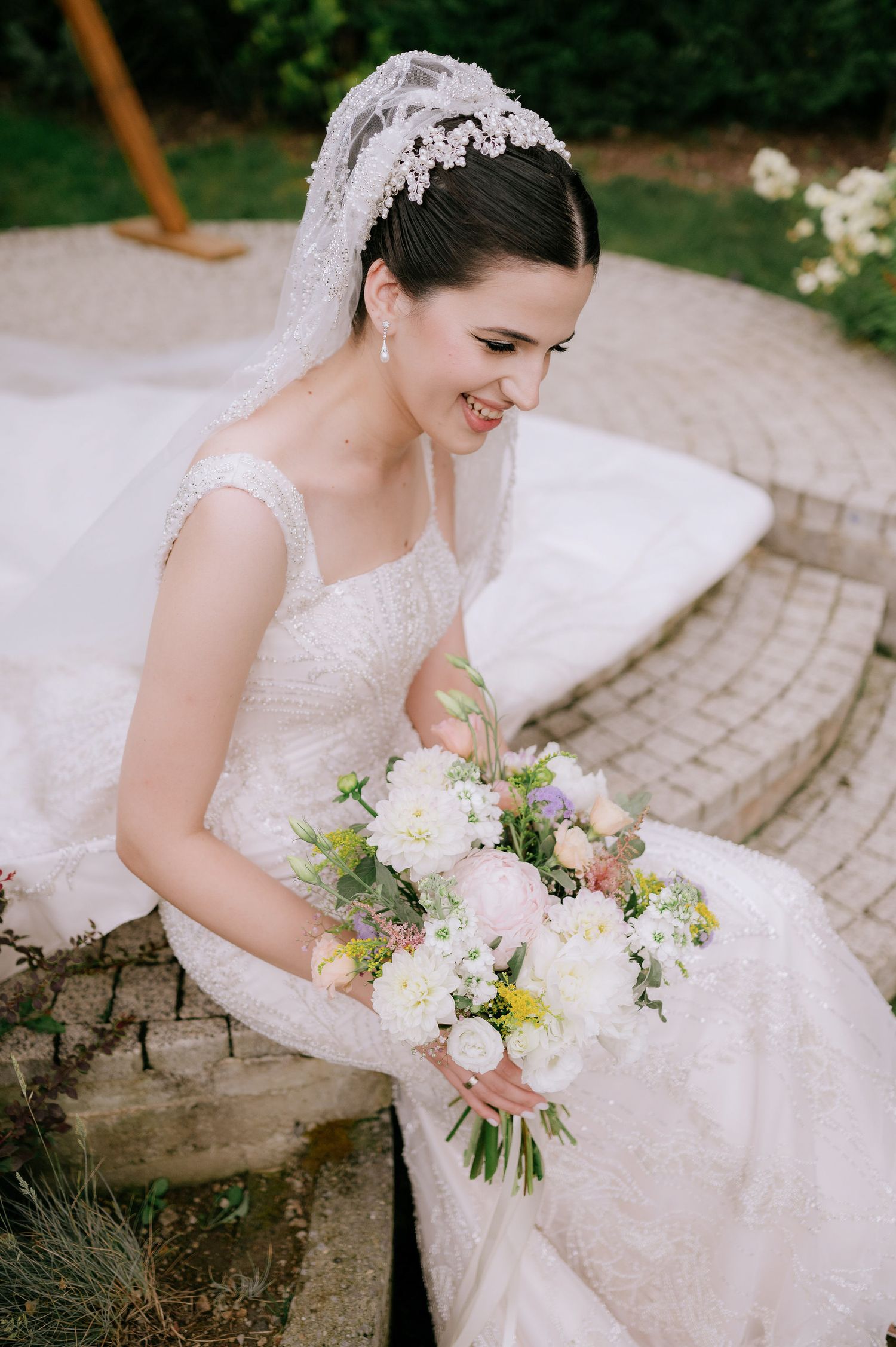 Elegant bridal portrait featuring white bouquet with mixed flowers and lace wedding gown.