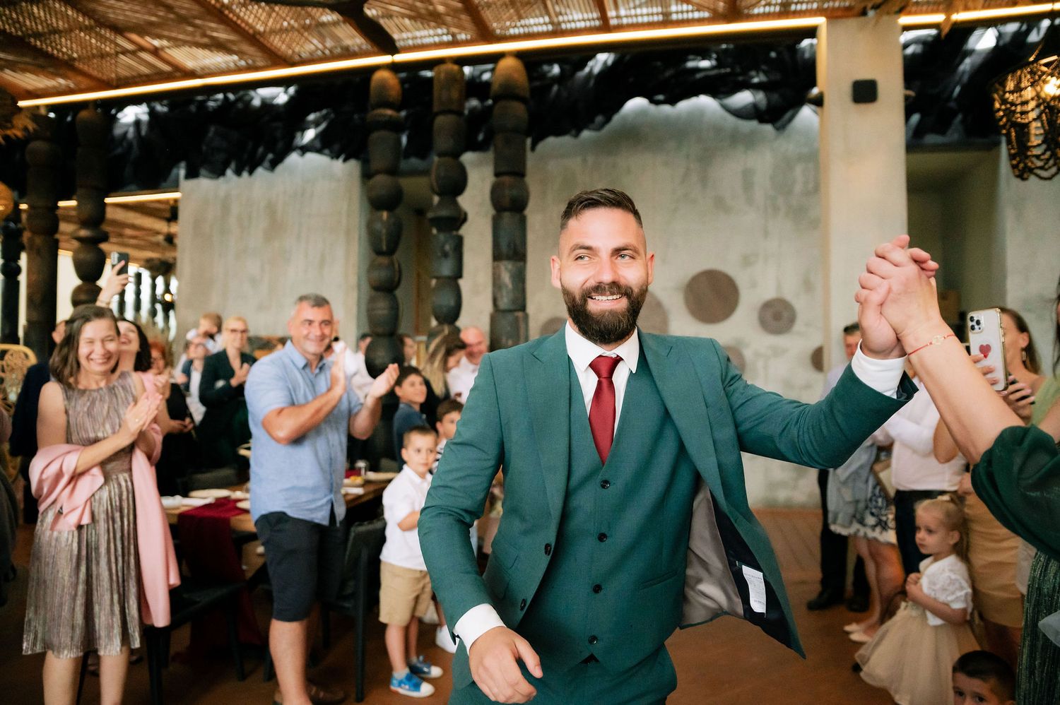 Celebratory moment at a wedding with guests clapping in an indoor venue.
