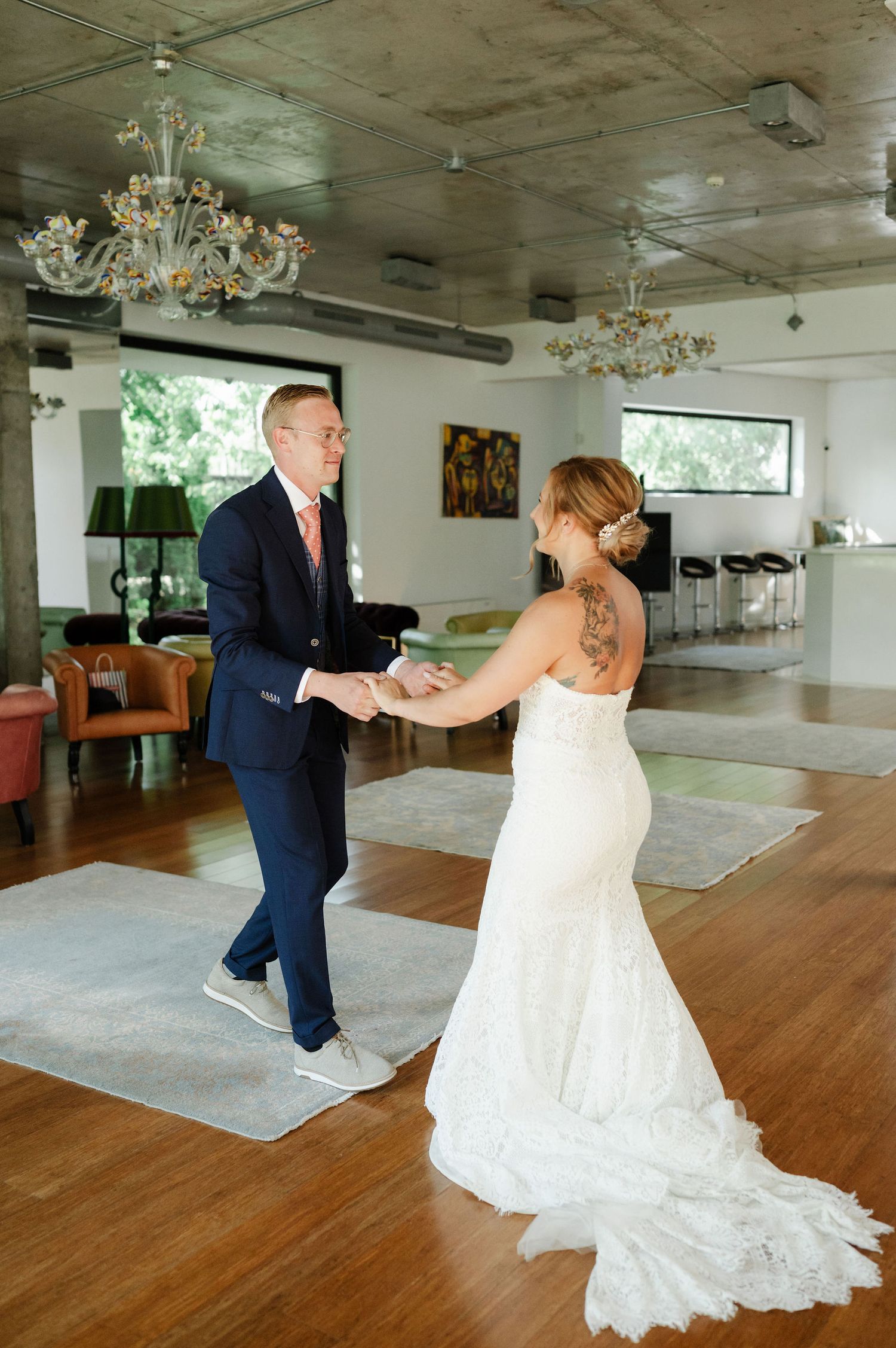 Bride and groom dancing energetically across hardwood floor during wedding reception.