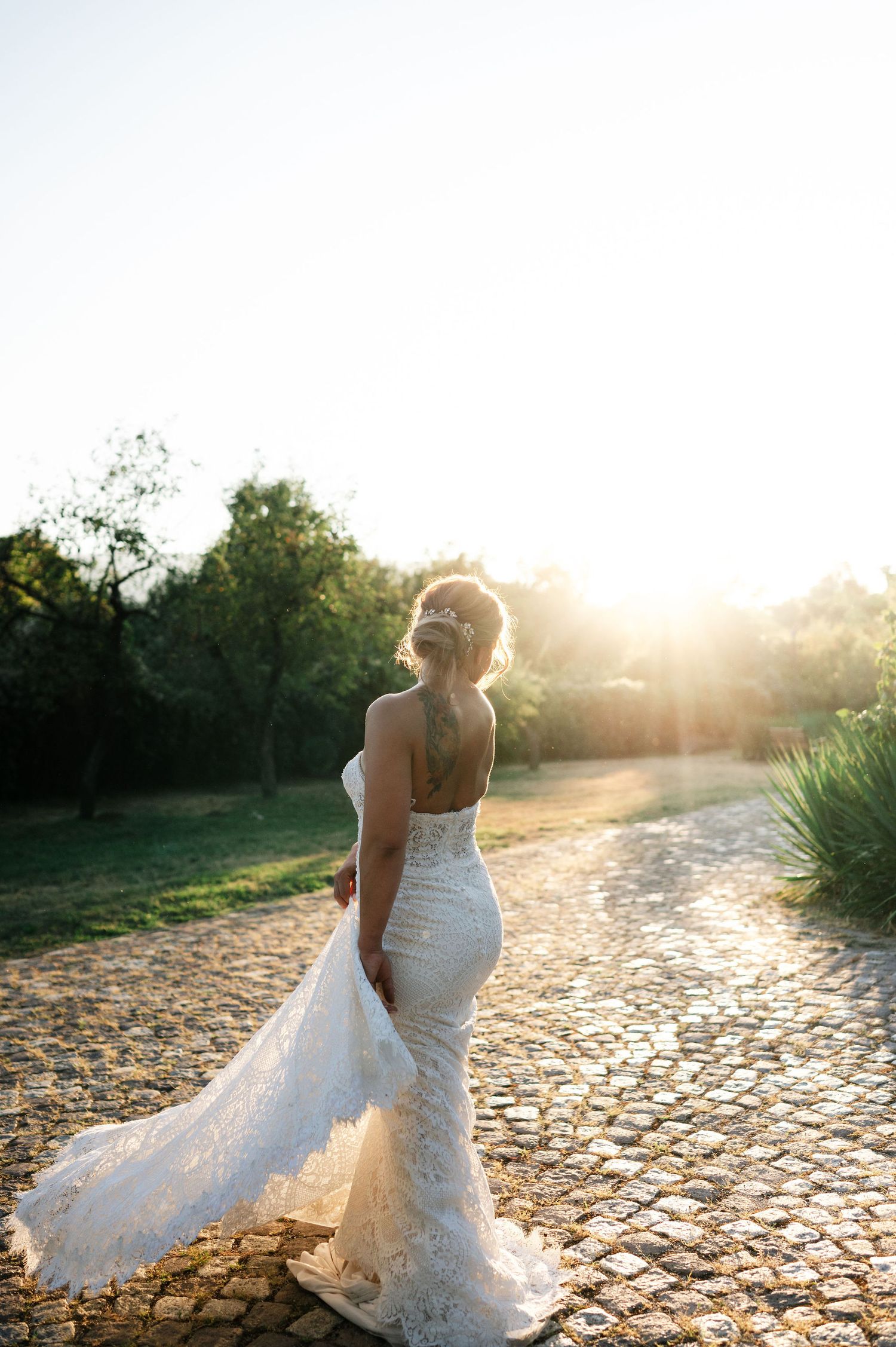 Elegant wedding dress movement captured against rustic cobblestones in warm evening light.