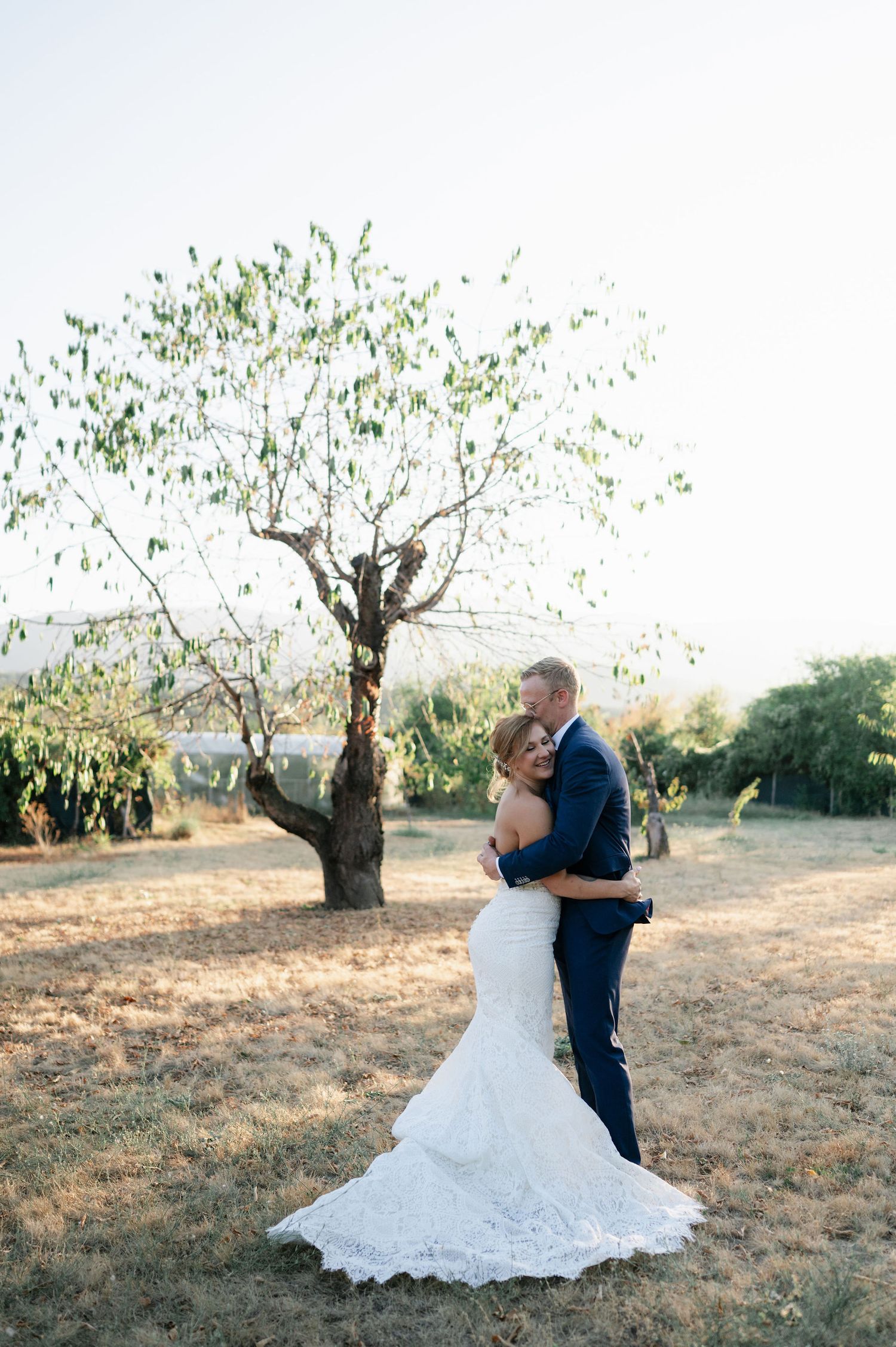 Couple sharing intimate dance moment in sunlit orchard.