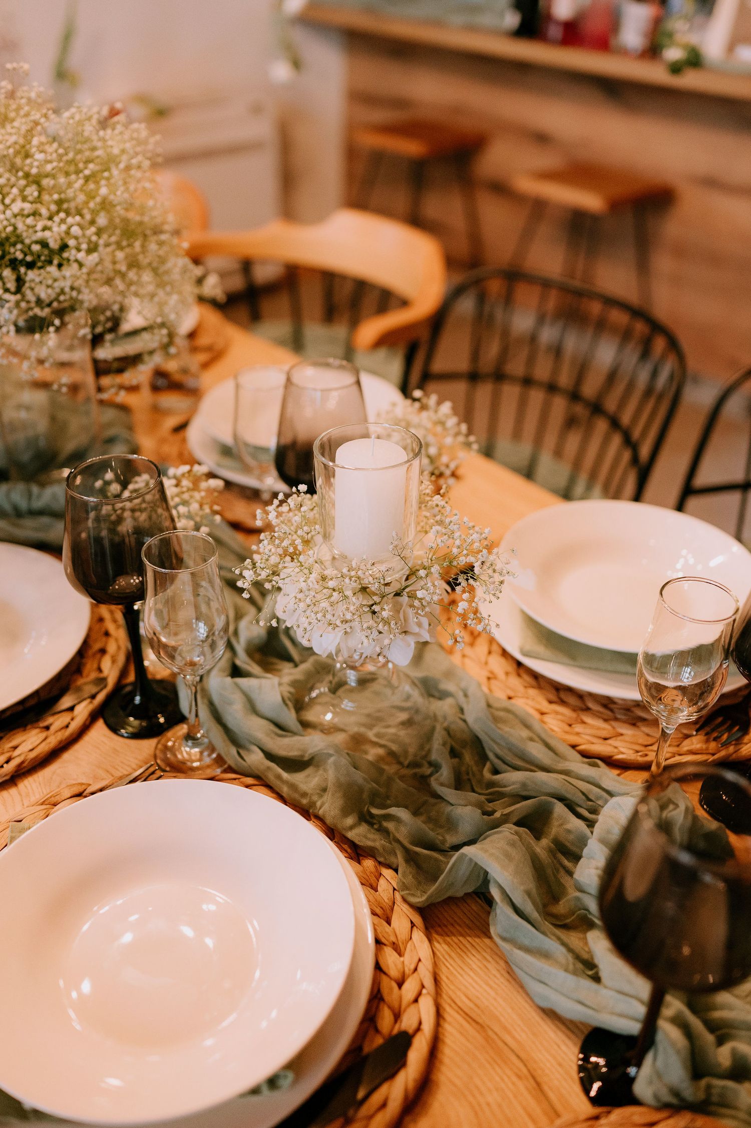 Elegant table setting with white plates, candles, and flowing fabric runner decorated with baby's breath flowers.