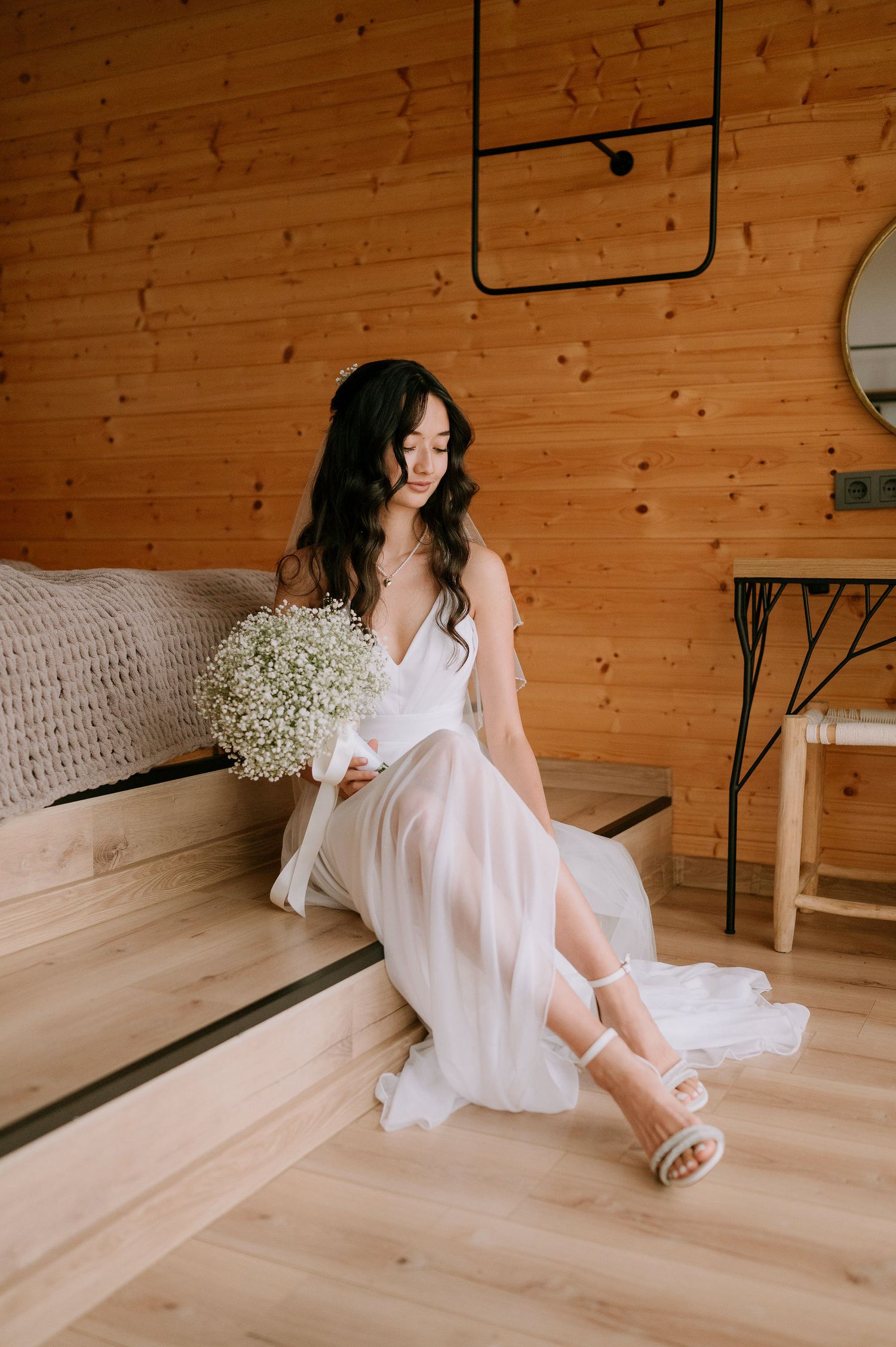 Ethereal bridal photo with white dress and delicate flowers against wooden paneled walls.