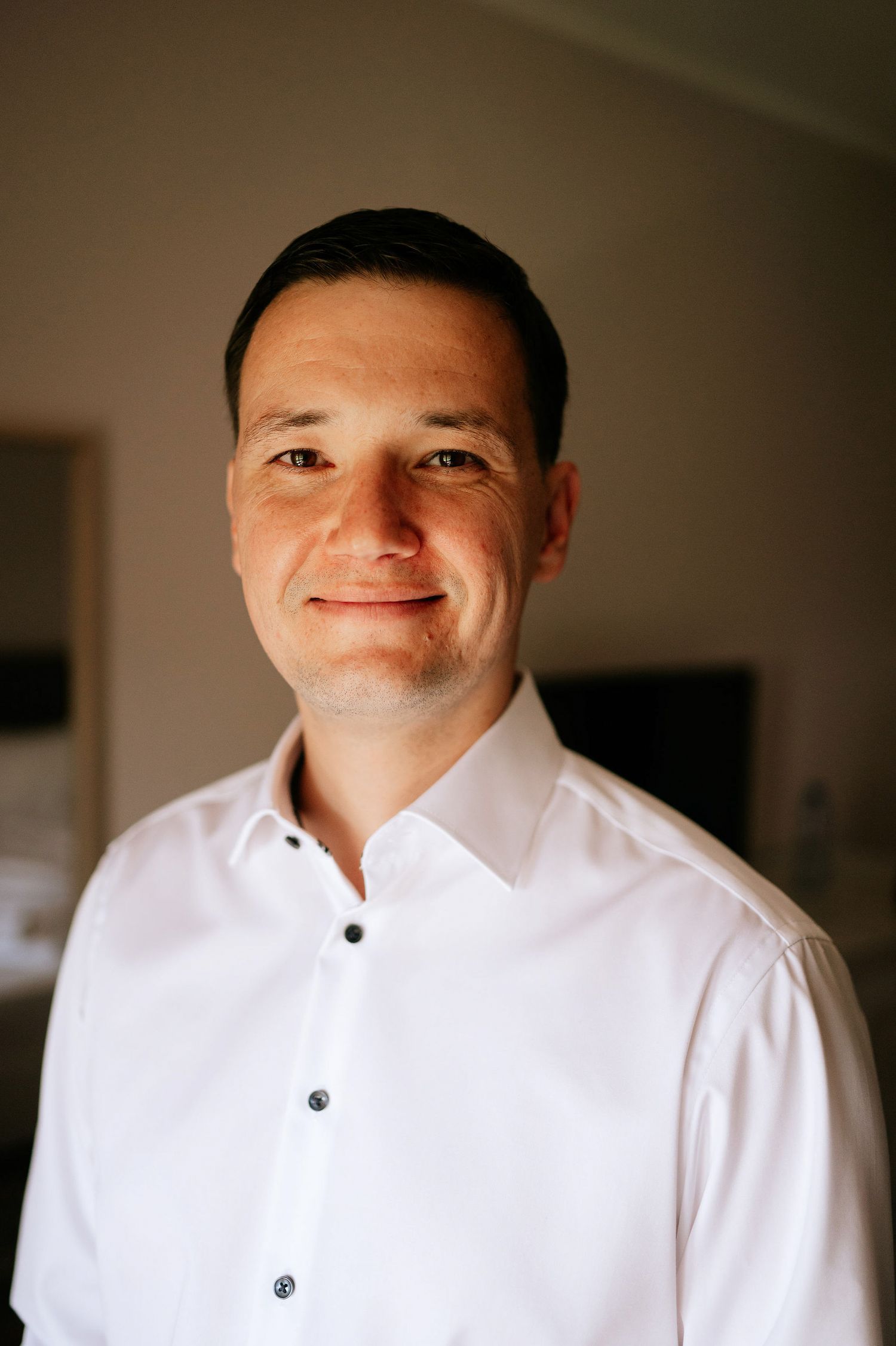 Person in a crisp white dress shirt smiling warmly at the camera.