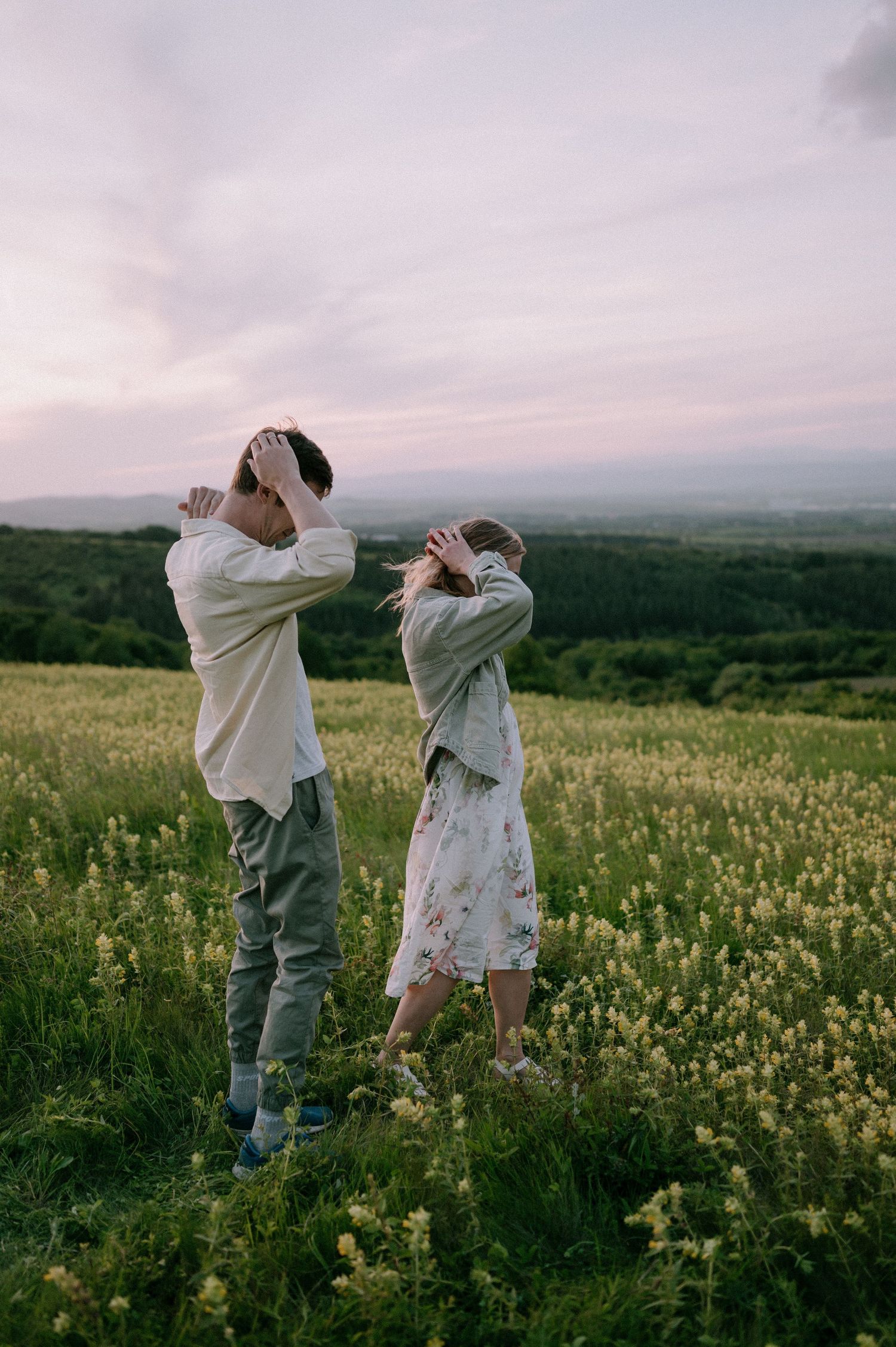 A couple dances playfully in a wildflower meadow at sunset with mountains in the background.