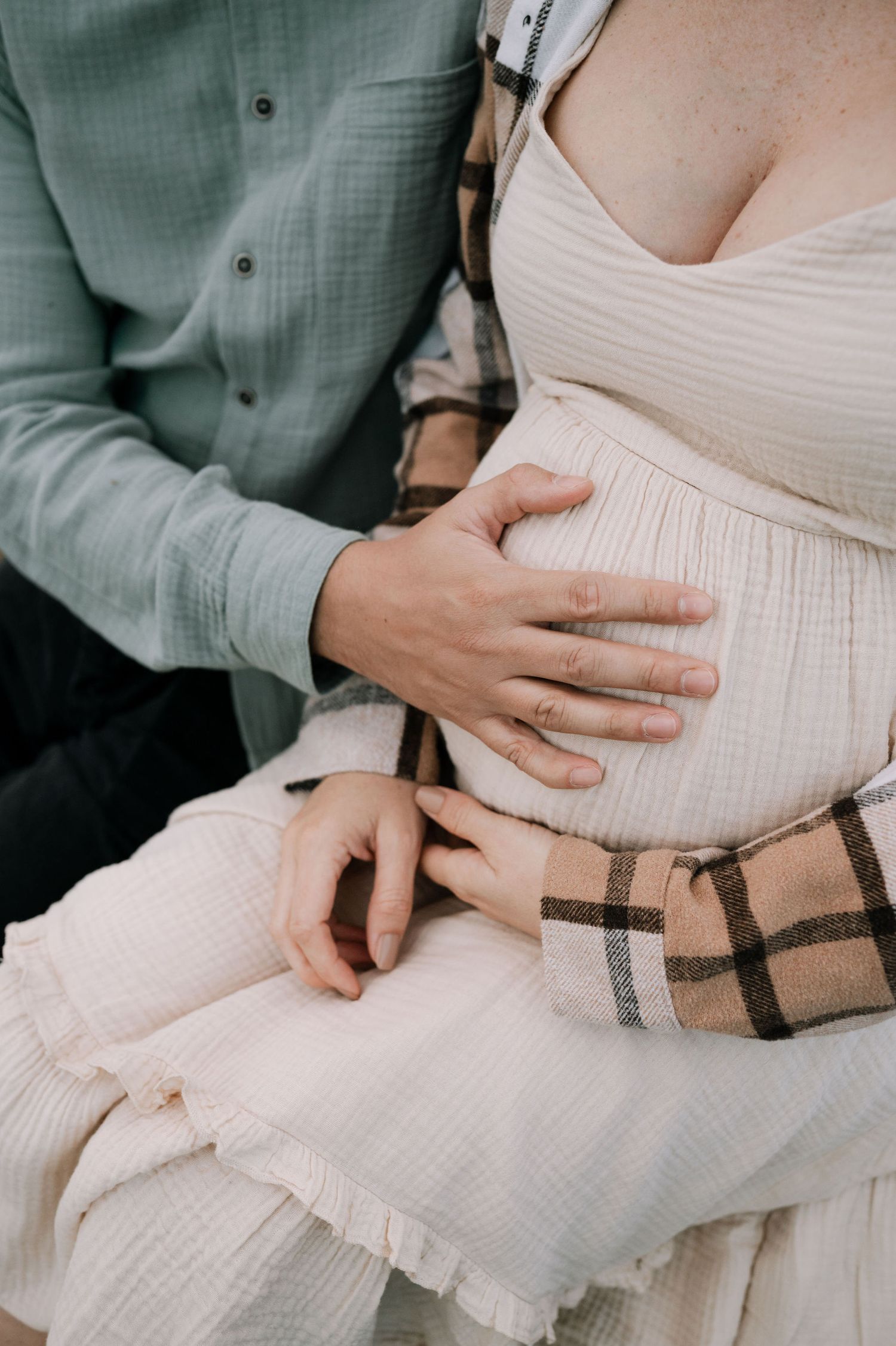 A series of intimate maternity photos showing hands gently cradling a pregnant belly in white dress against green shirt.