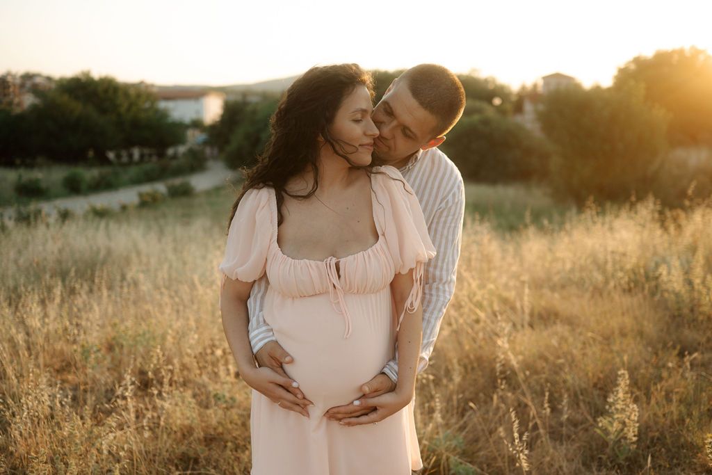 Intimate maternity portrait session photographed during golden hour in a rustic outdoor setting.