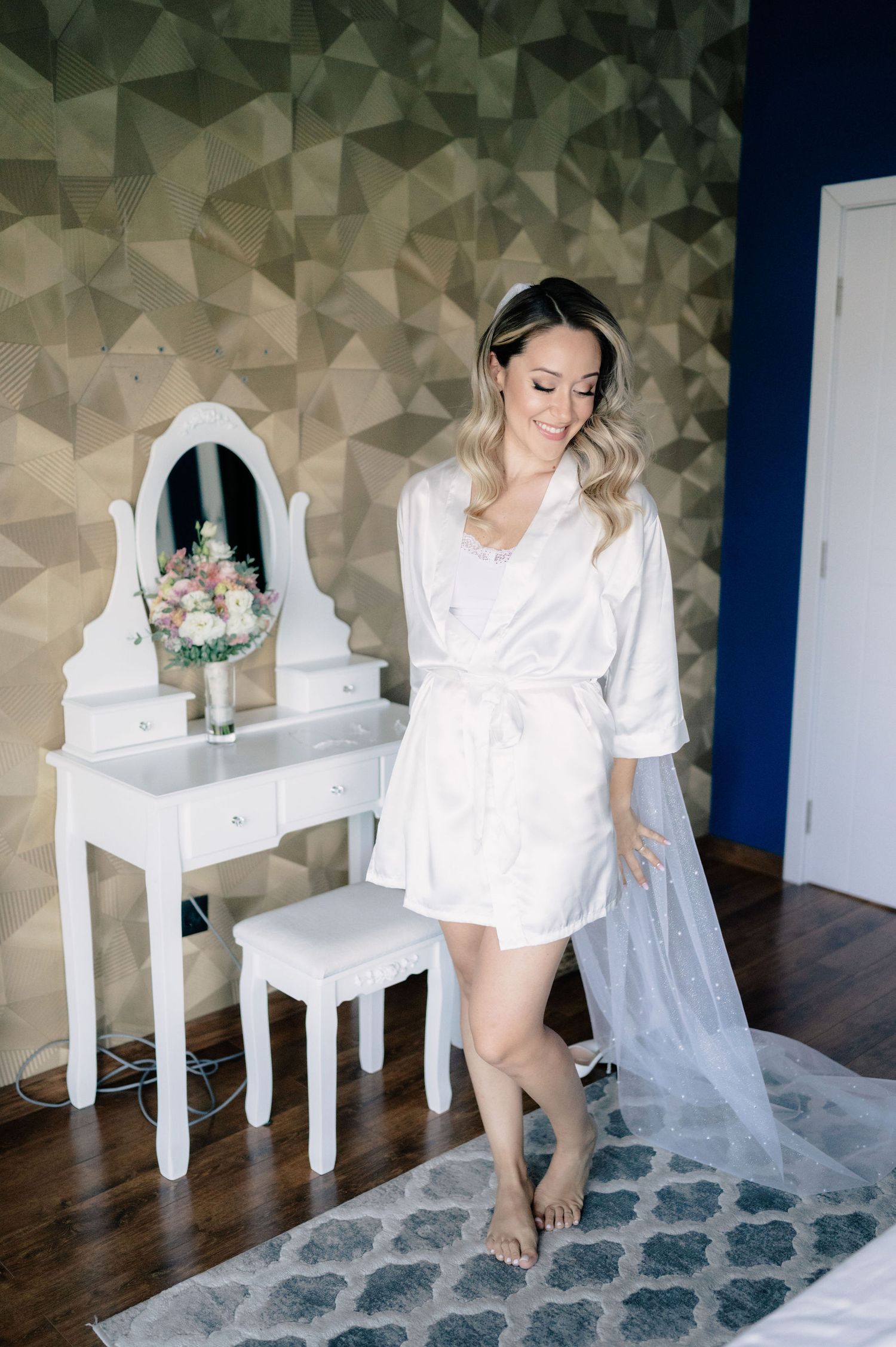 A series of photos showing a woman in white attire posing at a vanity table in a room with geometric wallpaper.