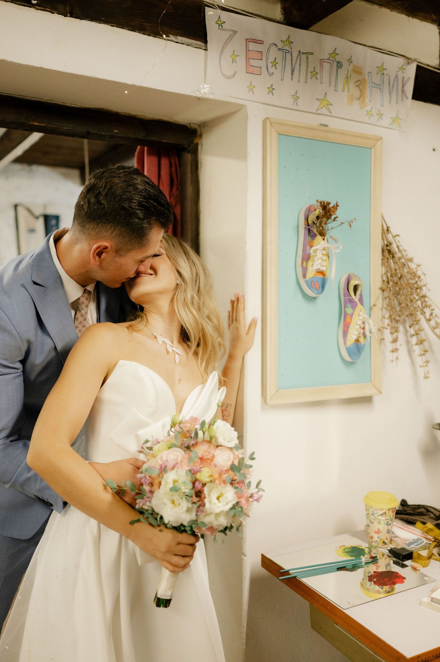 Romantic wedding moment captured in an art gallery with framed artwork visible on white walls in the background.