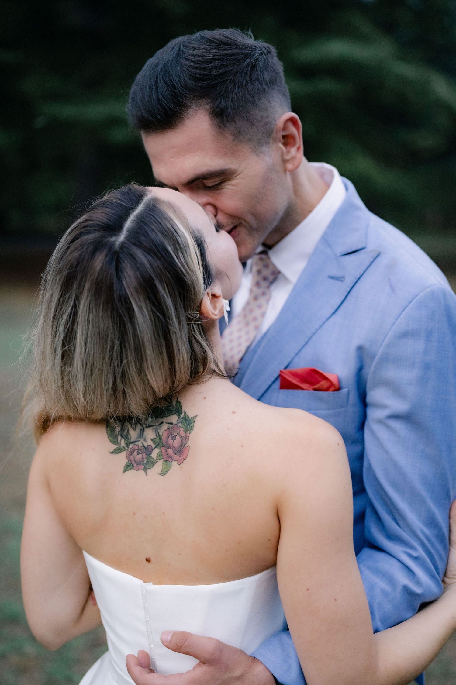 A couple in wedding attire share an intimate moment during a romantic outdoor photo session.
