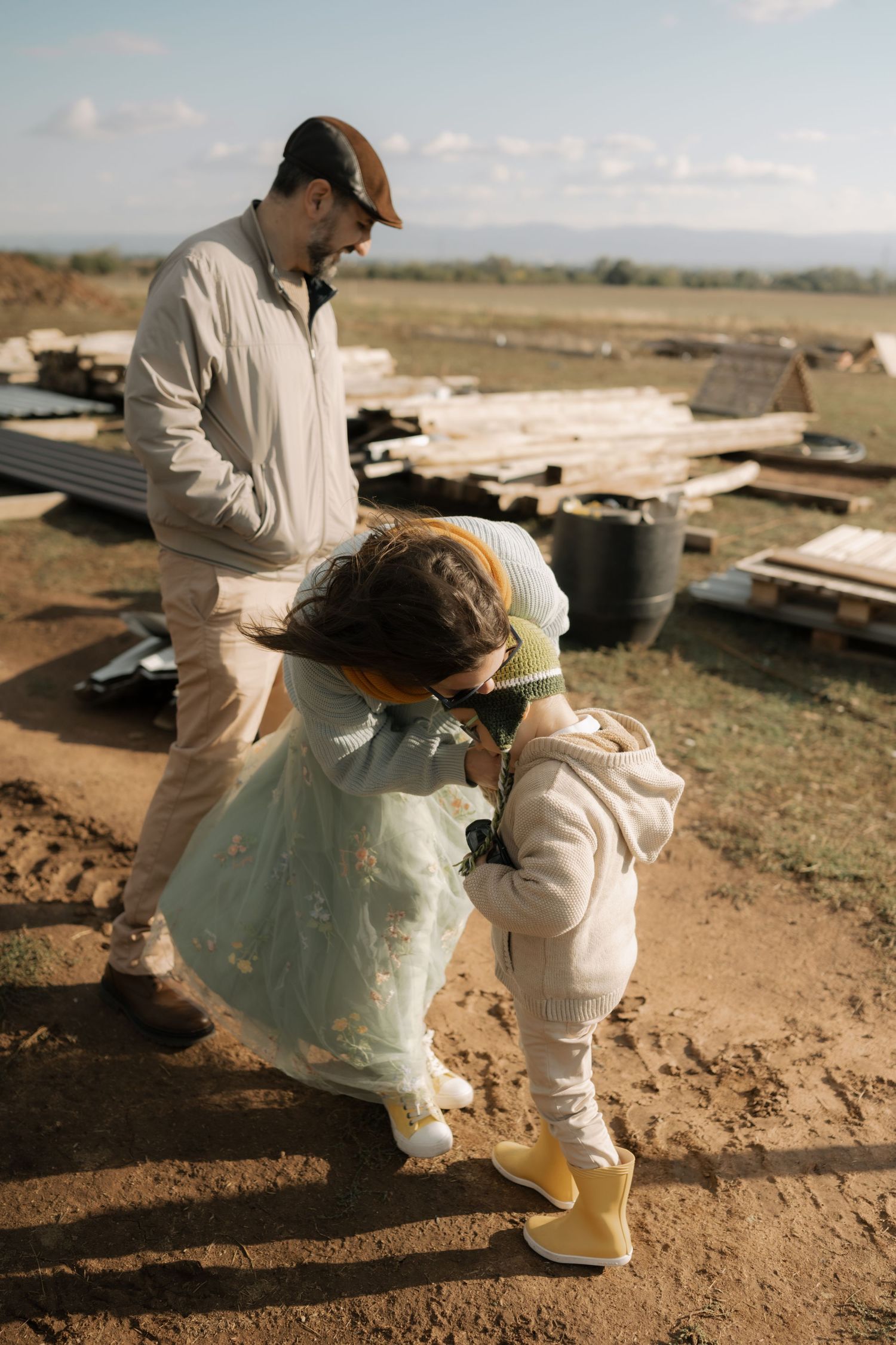 Two figures in white protective gear inspect debris on dusty ground in a desert landscape.