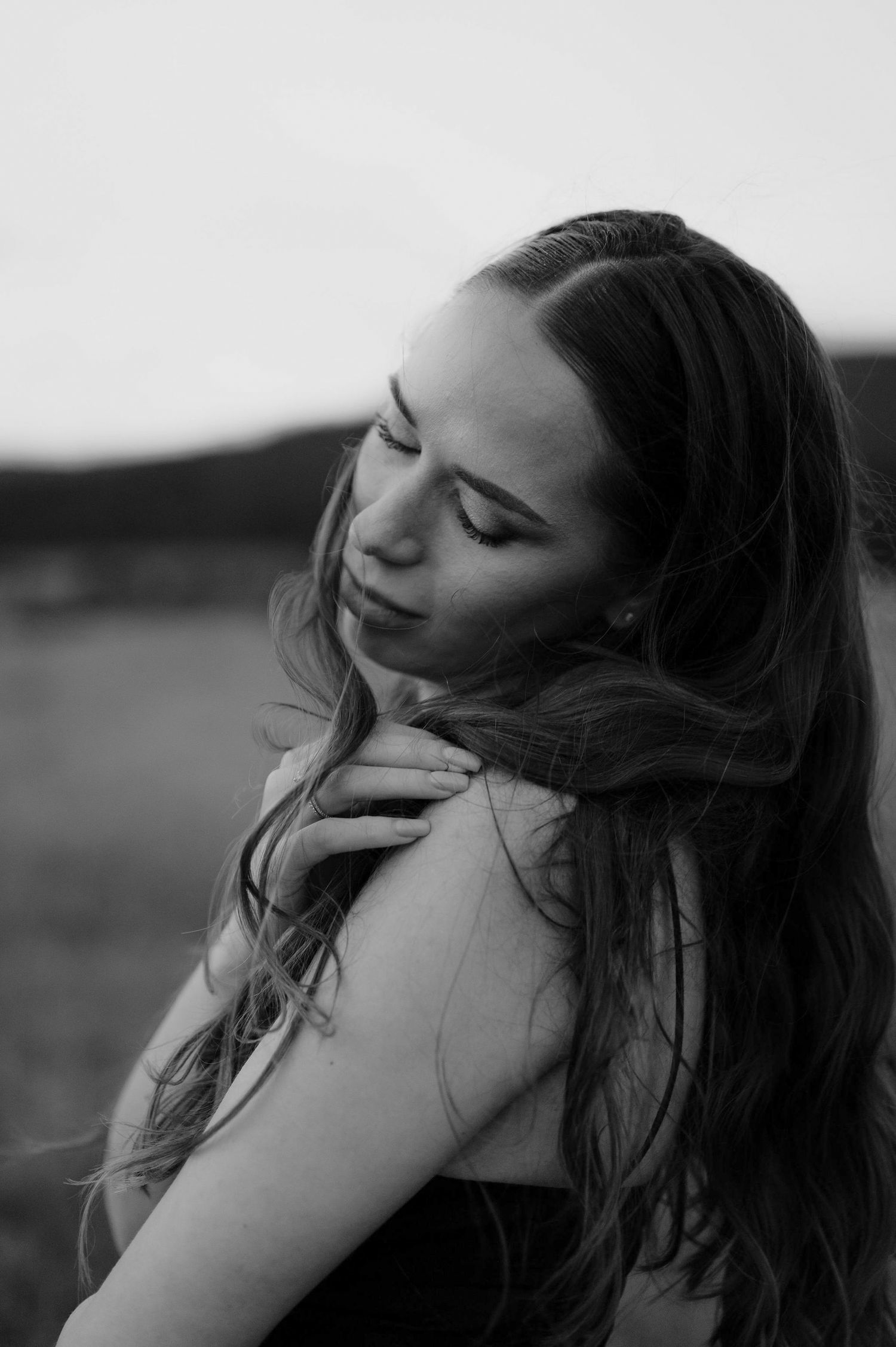 Black and white portrait series showing a woman with long hair smiling and posing against a blurred outdoor background.