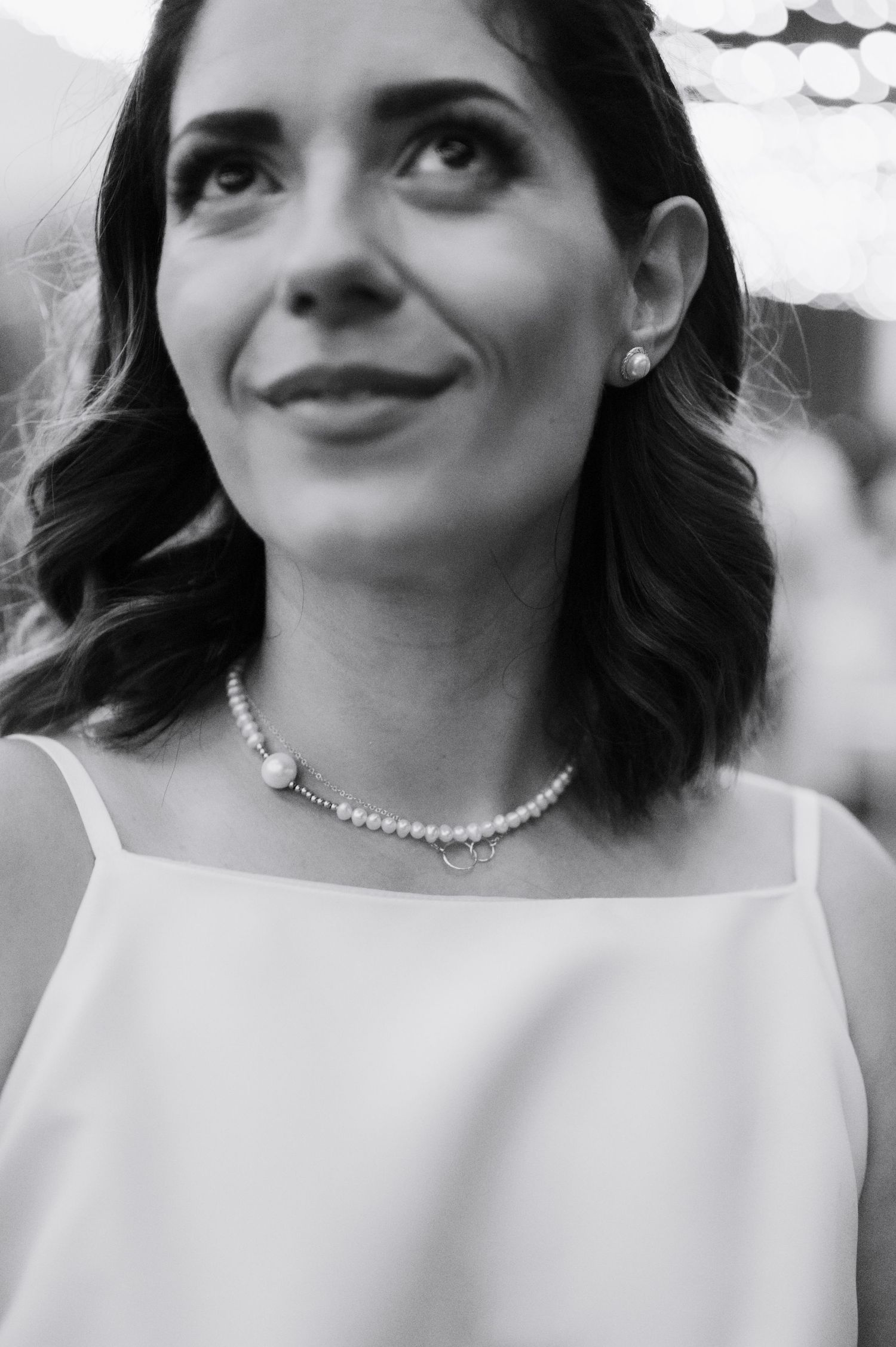A black and white portrait series showing a person wearing a white top and necklace with different expressions.