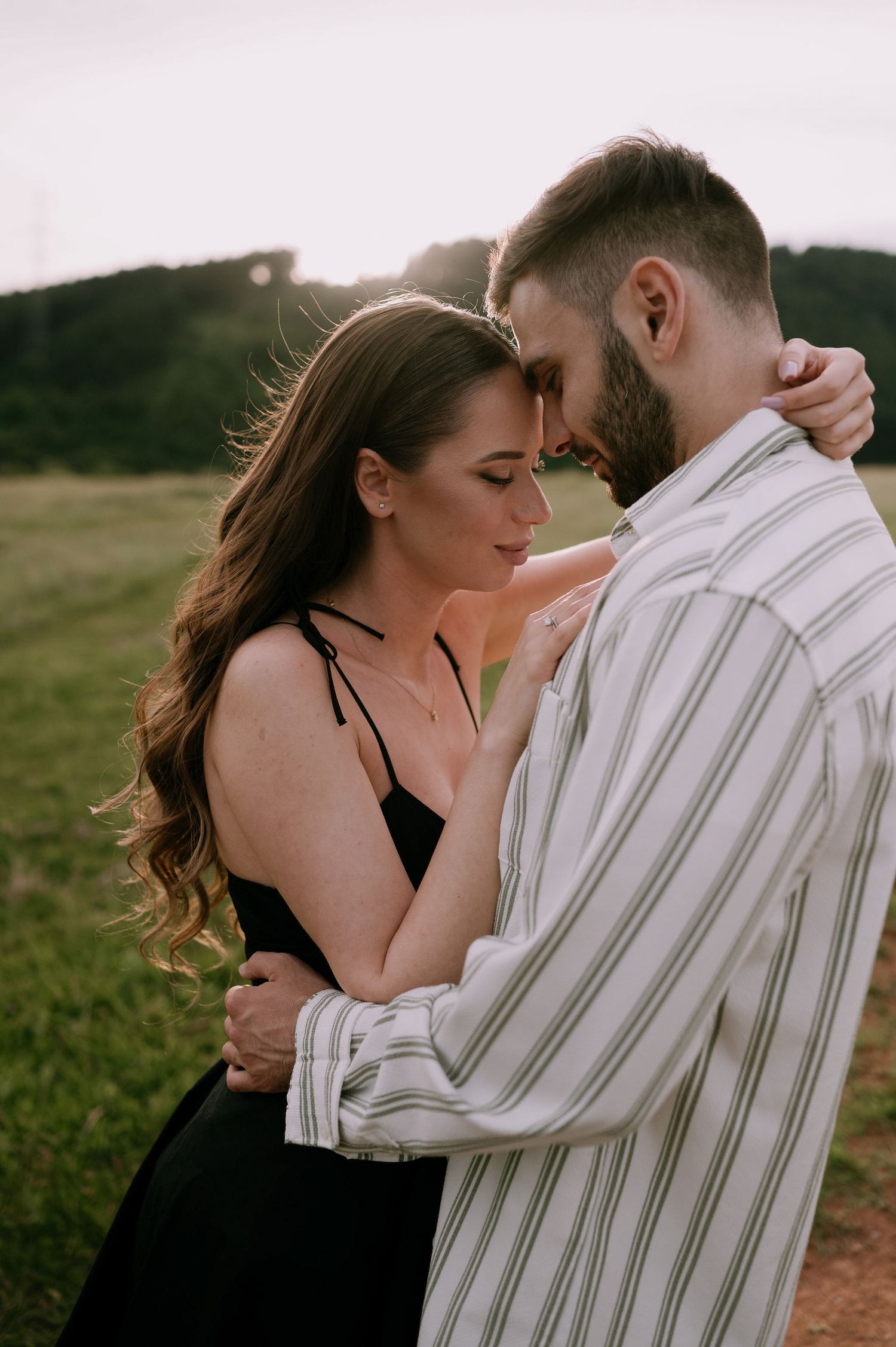 A romantic couple embraces in a field at sunset, with a series of intimate poses showing their tender connection.