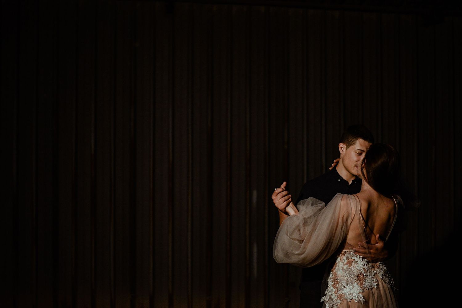 A person in a wedding dress dances gracefully in a dimly lit room during a reception celebration.
