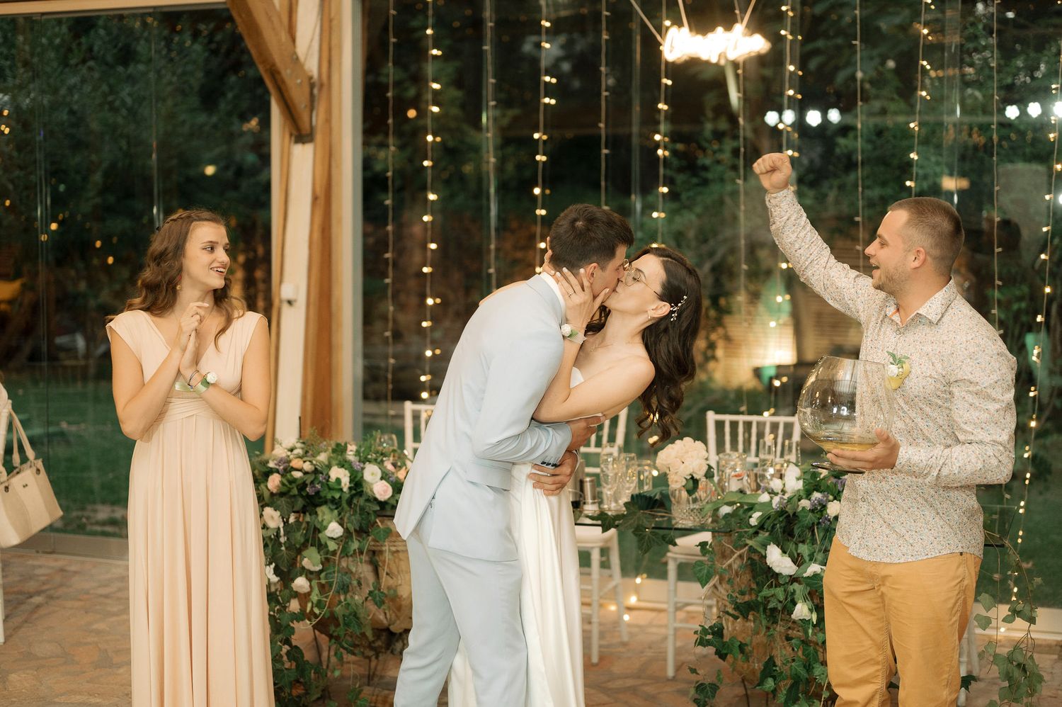 Wedding guests dance and celebrate together during an evening reception with twinkle lights and rustic decor.