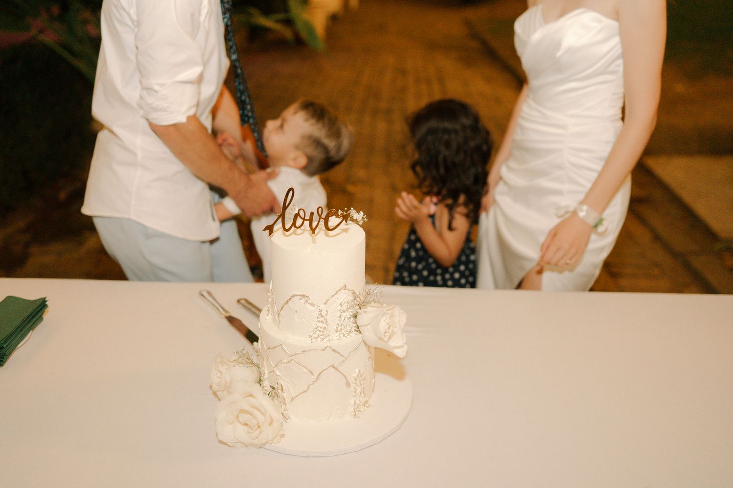 A person kneading and shaping white dough on a wooden surface in a professional kitchen setting.