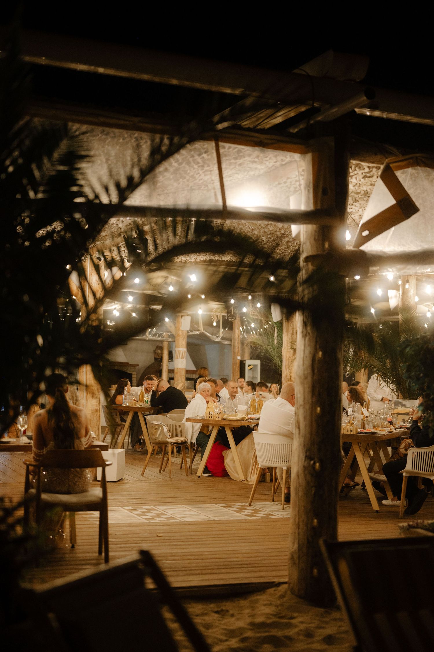 Warm-lit rustic restaurant interior with wooden beams and tables set for dinner service under ambient lighting.