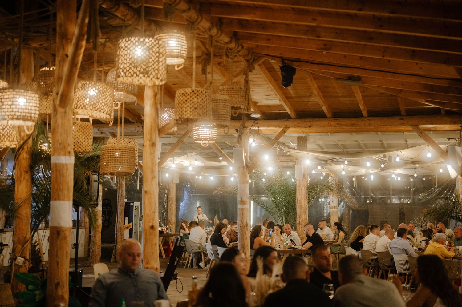 Rustic barn wedding reception venue with wooden beams and string lights creating a warm, romantic atmosphere.