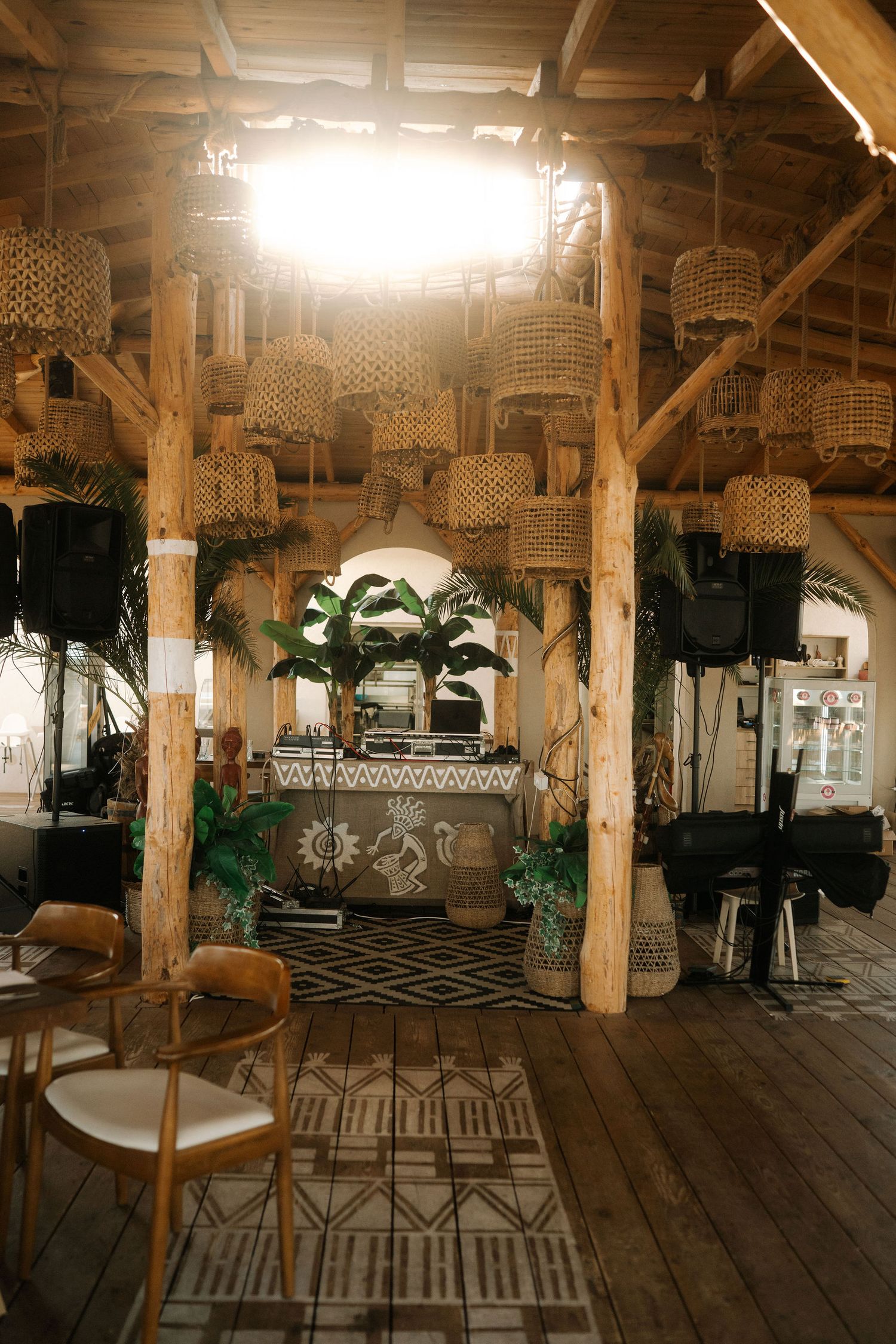 Rustic wooden interior of a restaurant with ornate carved pillars, wooden floors, and decorative lighting fixtures.