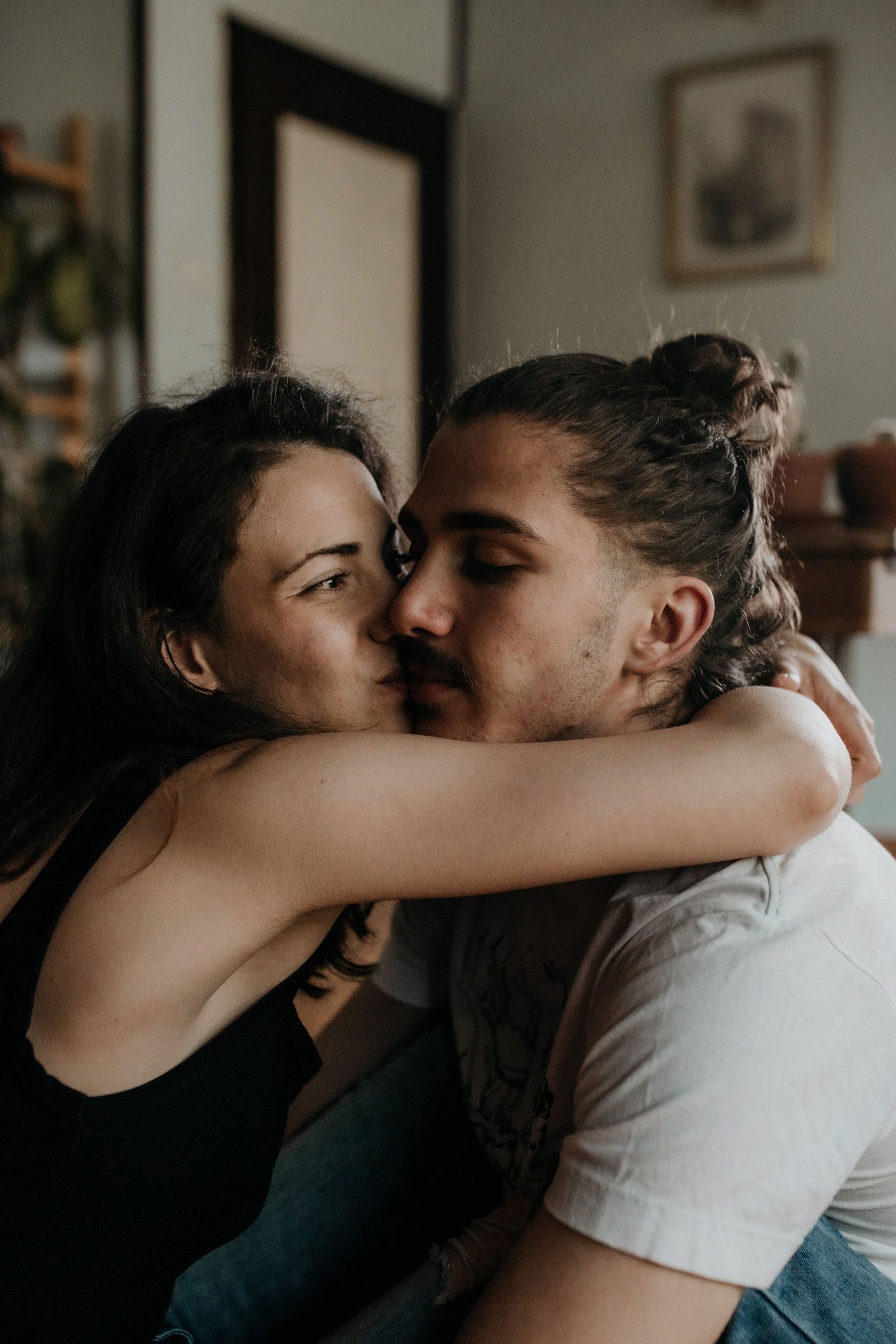 Intimate sequence of couple embracing and kissing in a cozy indoor setting with natural lighting.