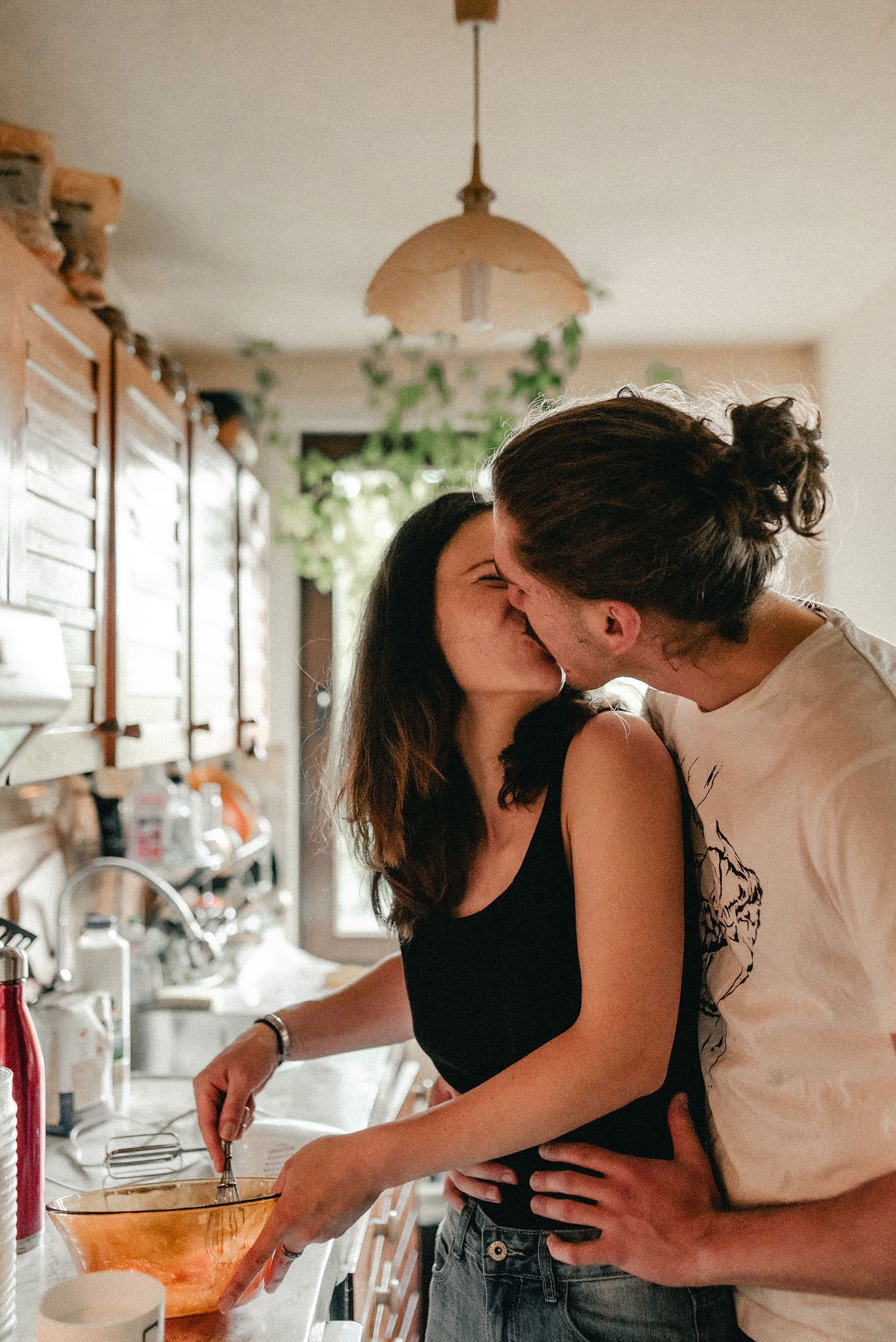 A romantic couple sharing intimate moments while cooking together in a bright, modern kitchen.