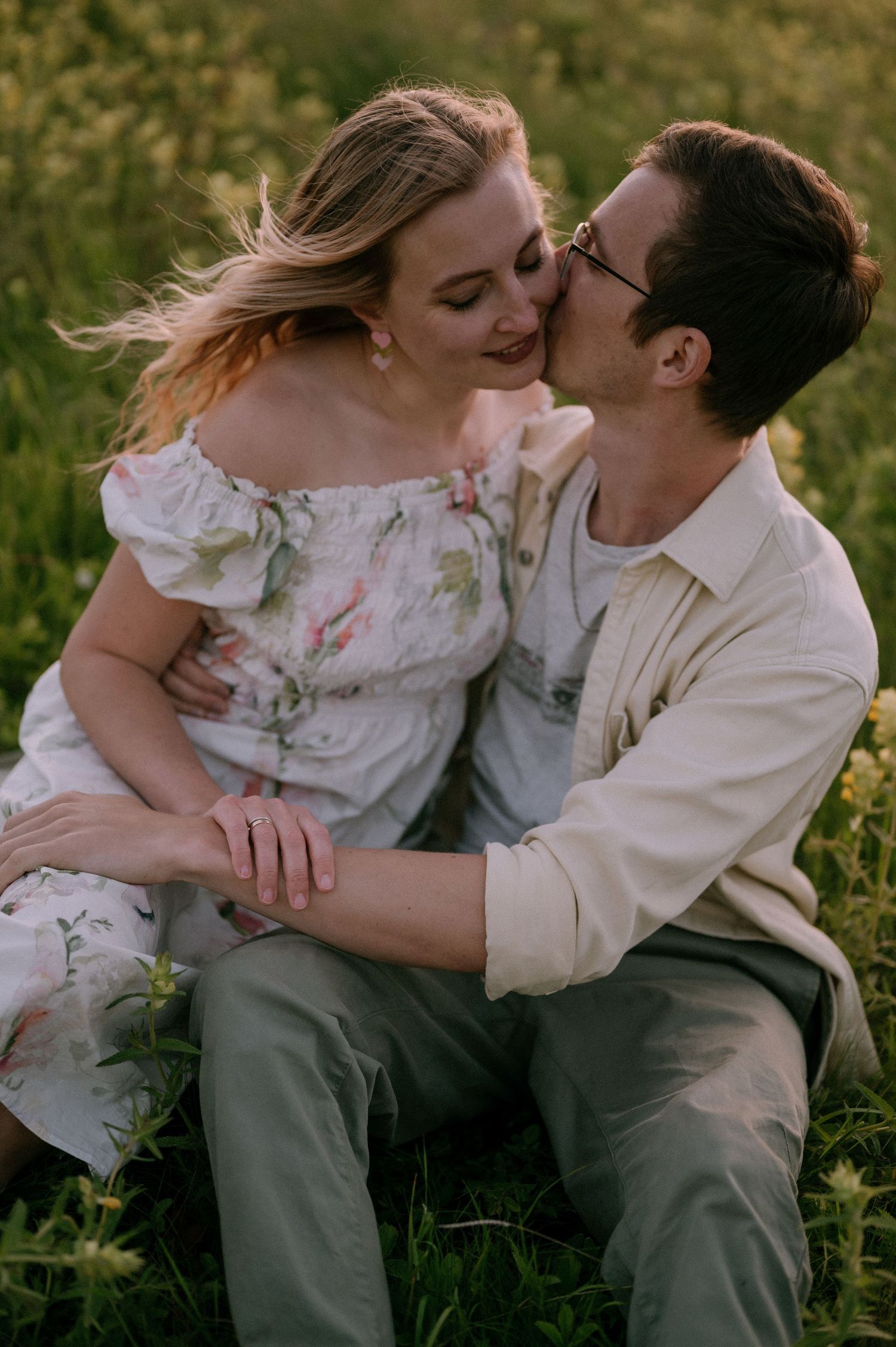 Tender embrace captured in flowering meadow with soft evening light.