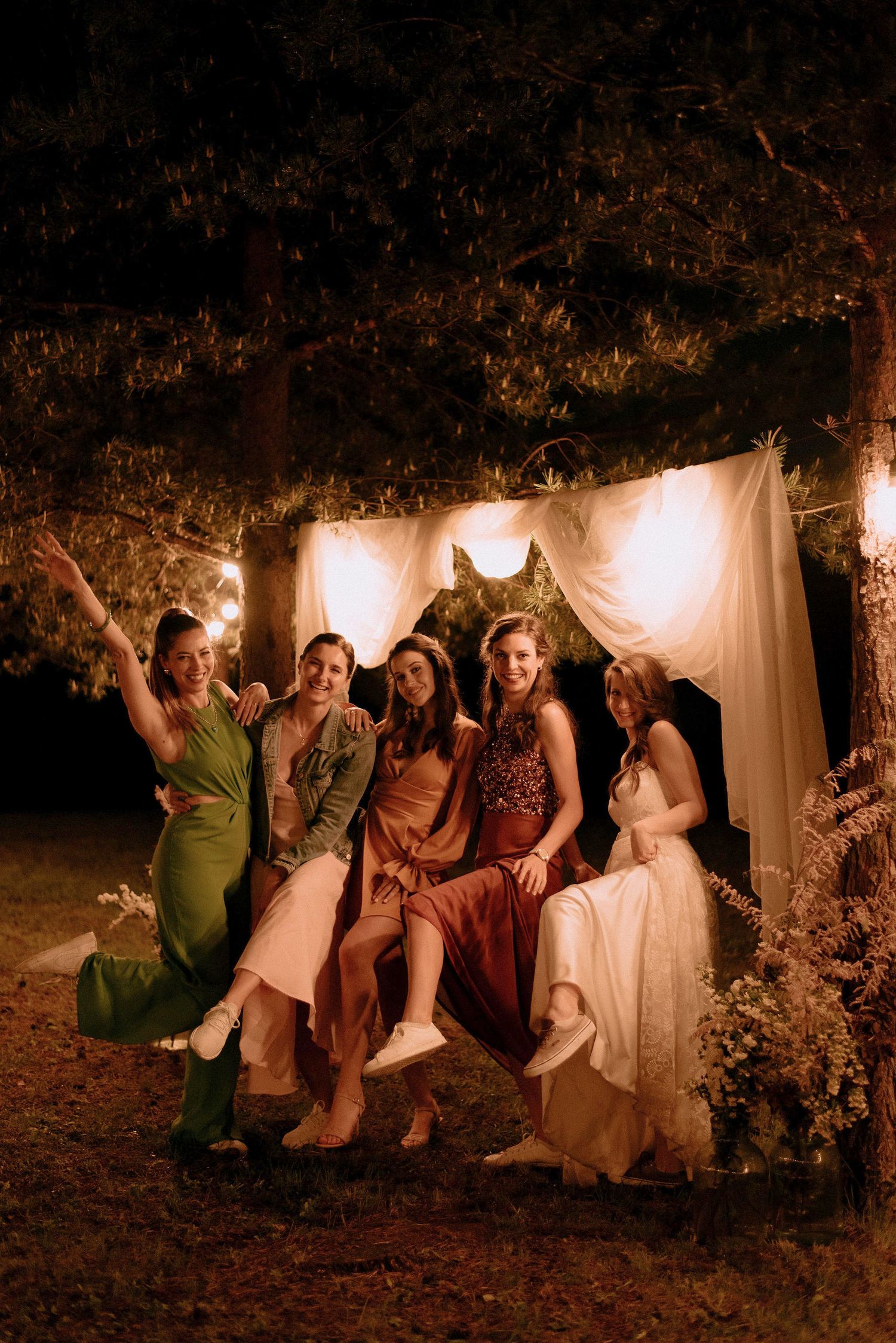 Group photo session against white backdrop with string lights in a nighttime garden setting.