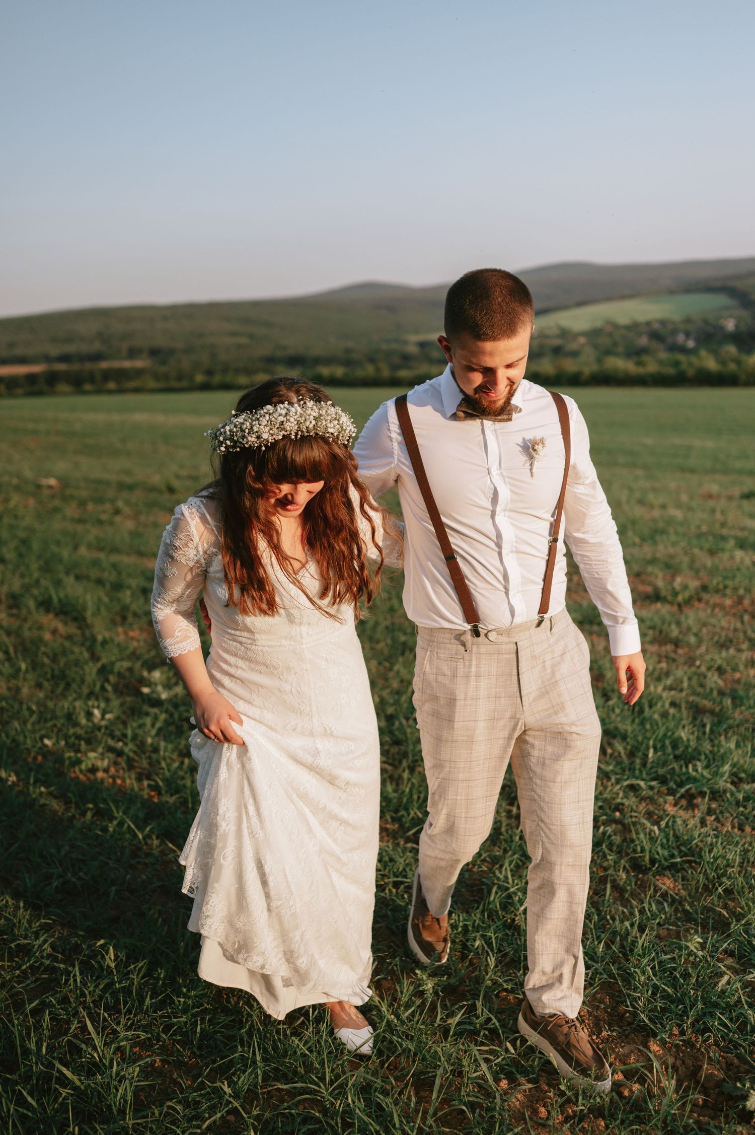 Wedding couple walking together on hillside with scenic mountain views.