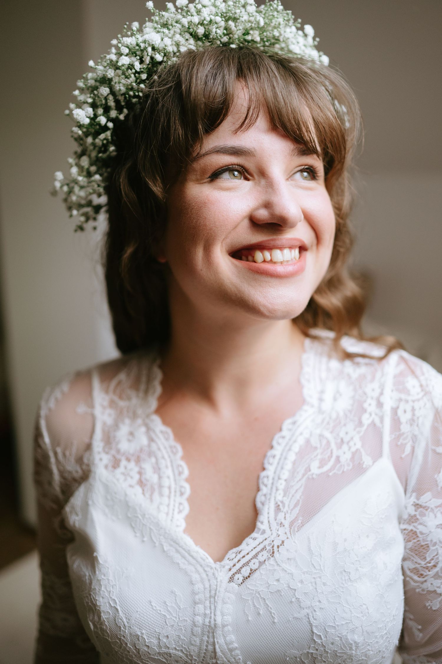 Close-up of delicate lace wedding dress with floral crown details.