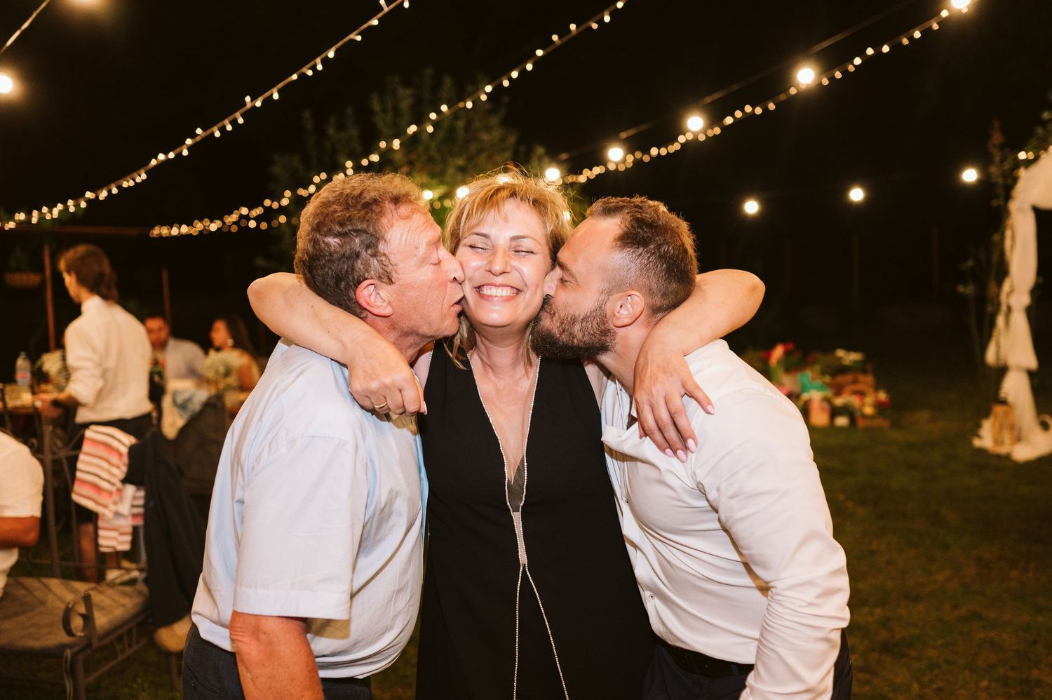 Friends share an enthusiastic group hug during an outdoor evening celebration.