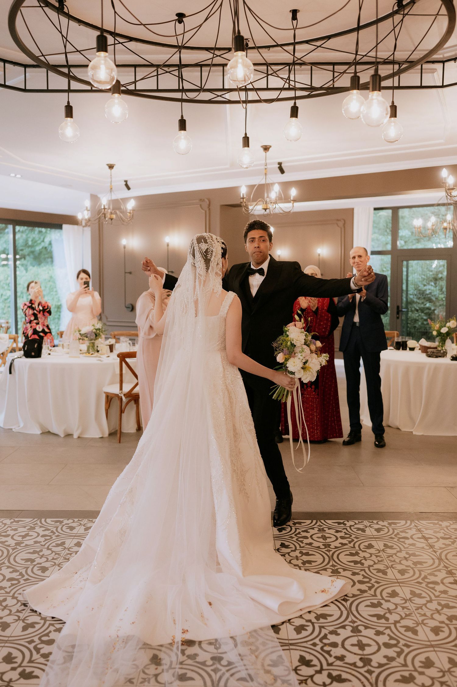 Elegant wedding reception venue with string lights, patterned floors, and white decor details.