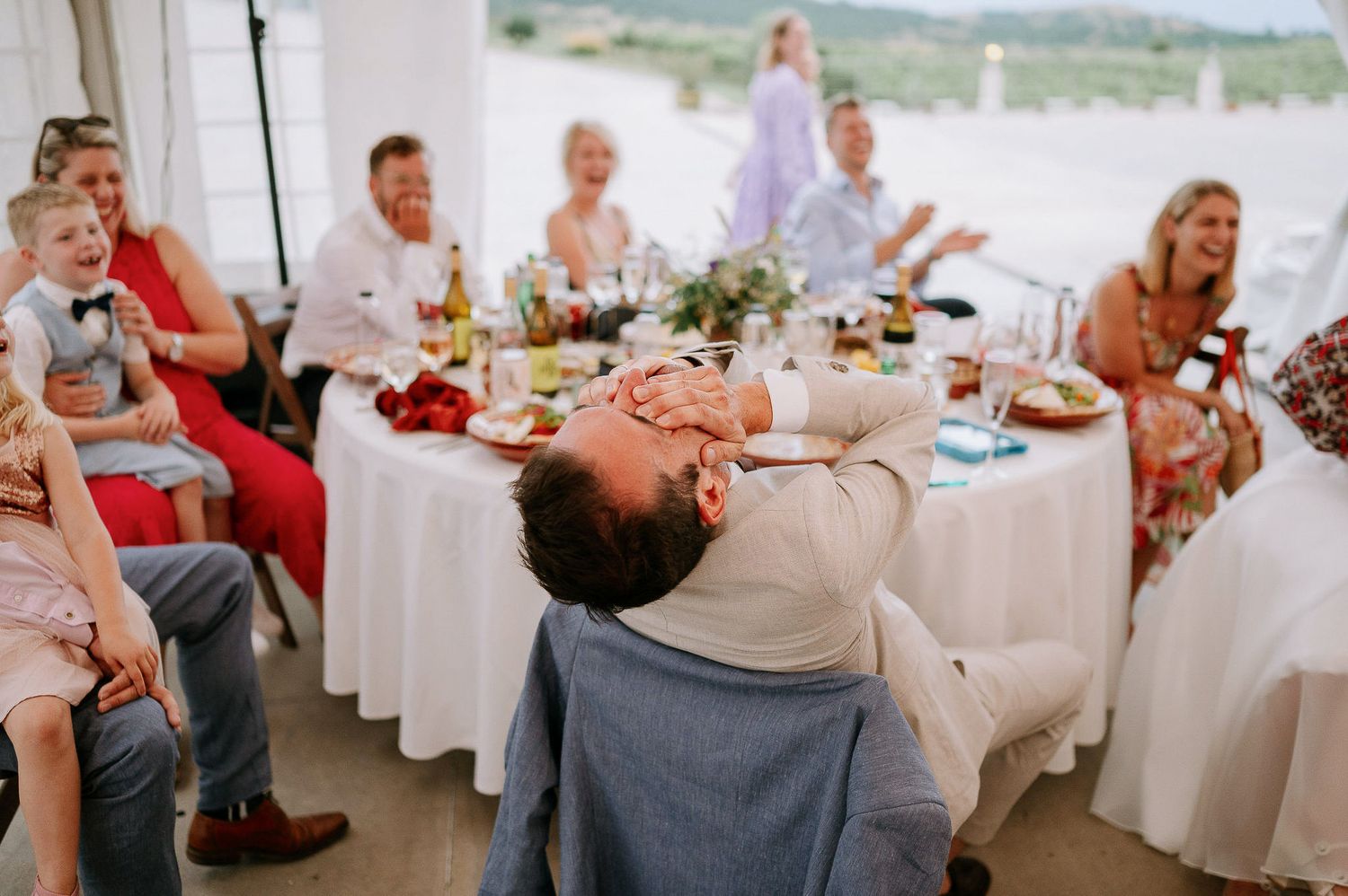 Wedding reception setup with white-covered tables and scenic outdoor views through large windows.