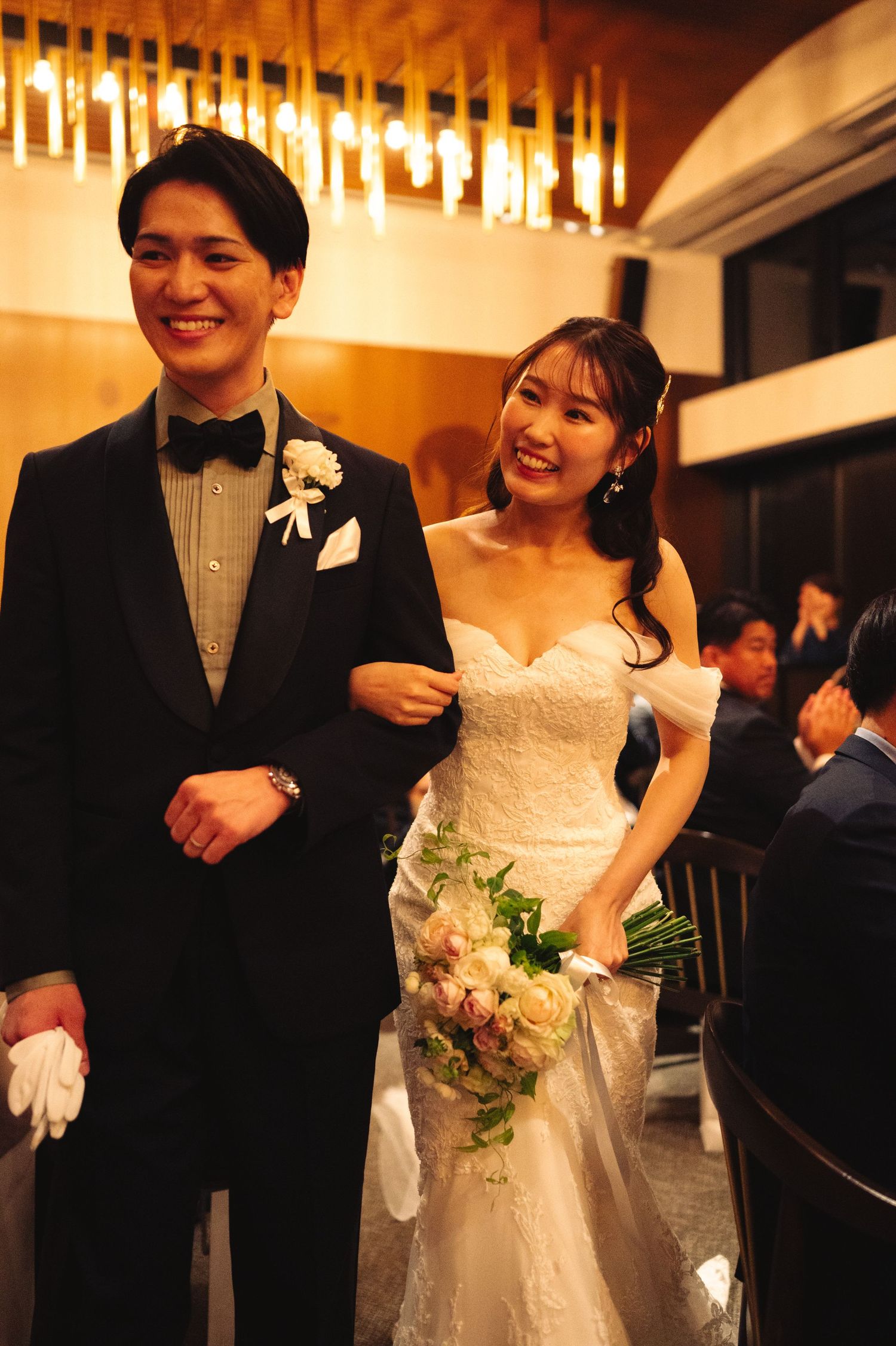 Happy couple sharing candid moments during their wedding reception under ambient lighting.