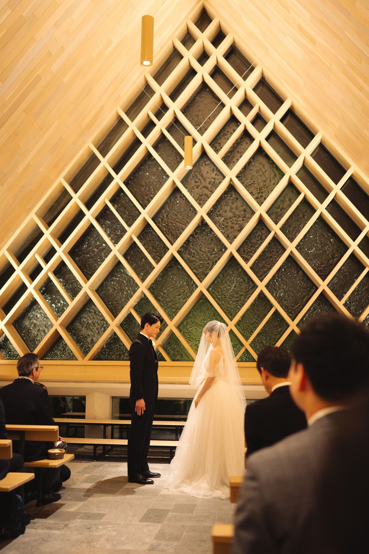 A wedding ceremony in a modern chapel with distinctive diamond-patterned wooden lattice architecture.