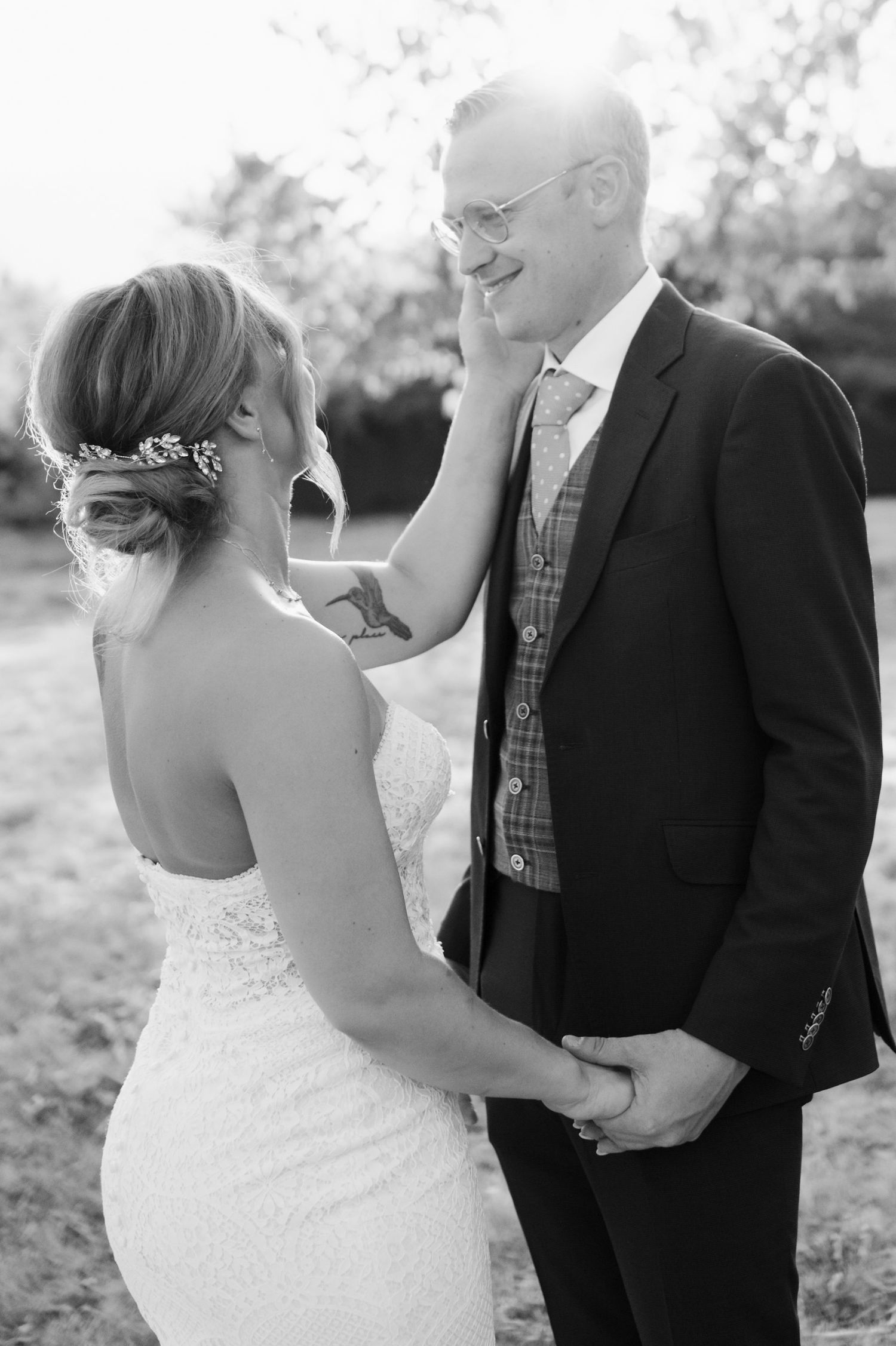 A romantic black and white portrait of newlyweds sharing an intimate moment in a rustic outdoor setting.