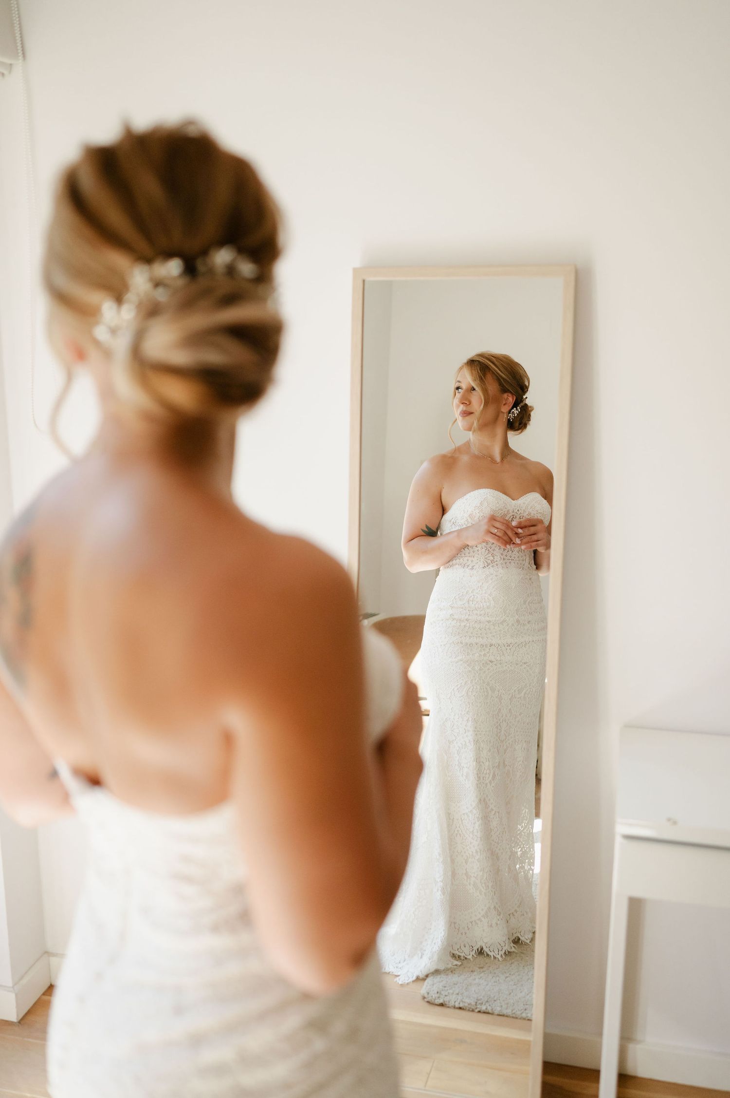 A series of elegant bridal portraits showing the back details of a white lace wedding gown in a bright room.