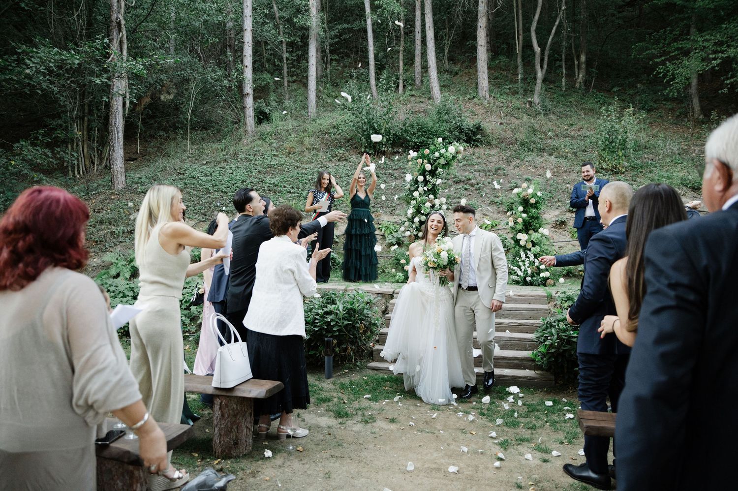 Forest wedding venue with natural stone steps and wooden seating surrounded by trees.