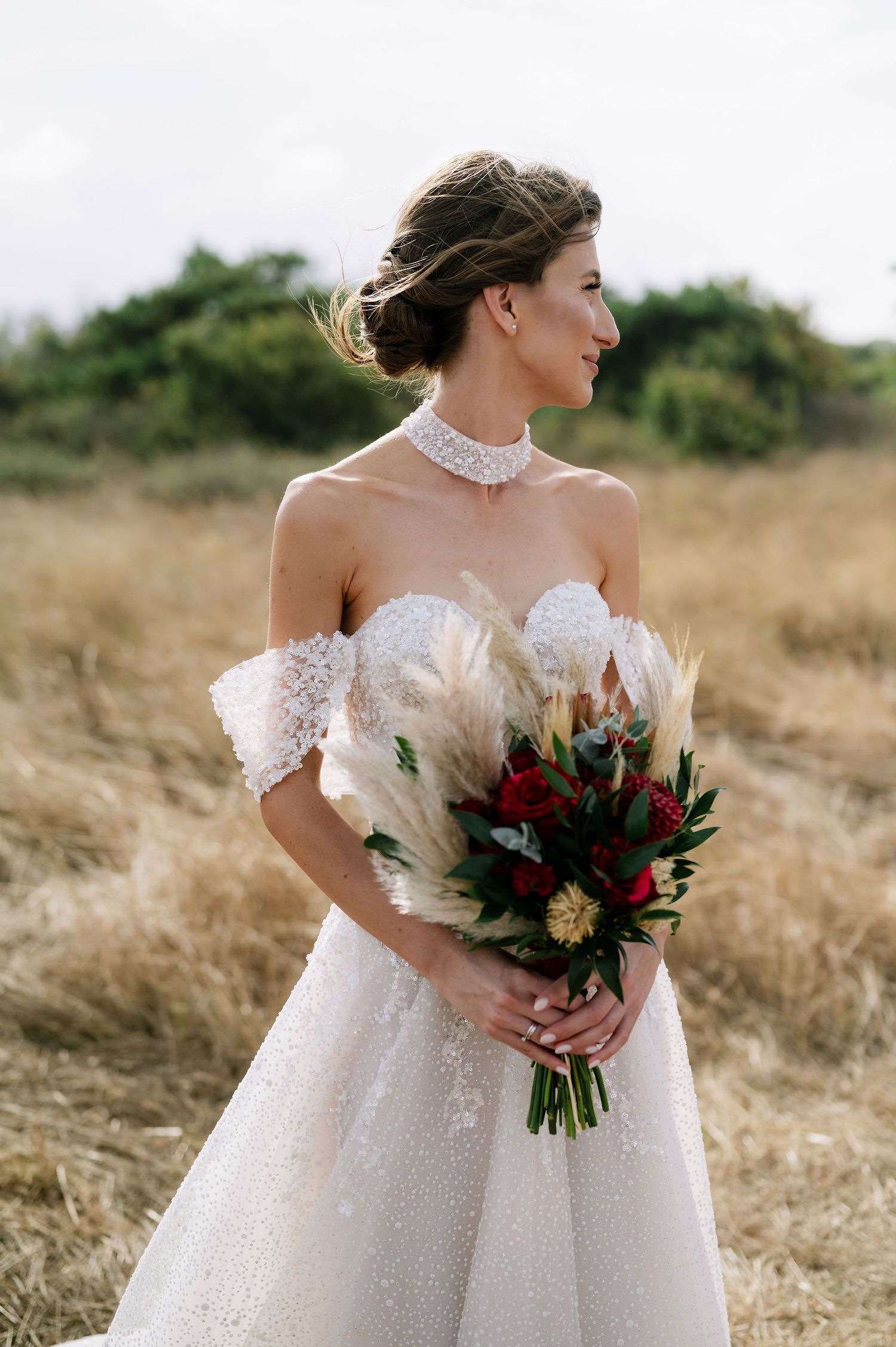 Candid shot of a bride in a princess ballgown holding a rich burgundy and greenery bouquet.
