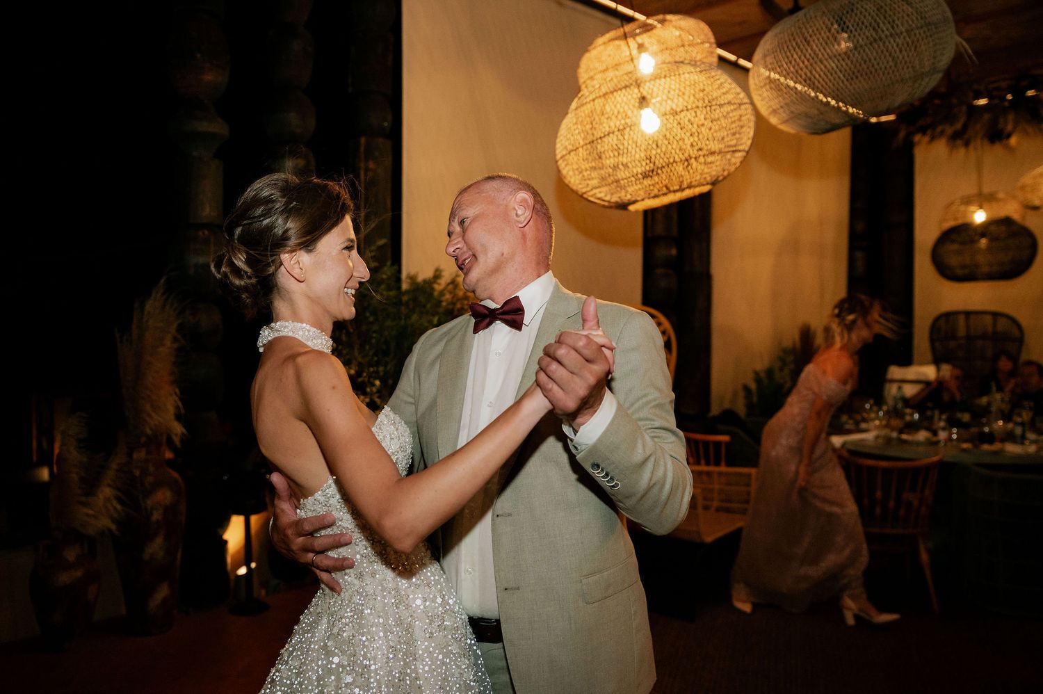 Couple sharing an intimate dance moment under warm pendant lighting at an elegant wedding reception.