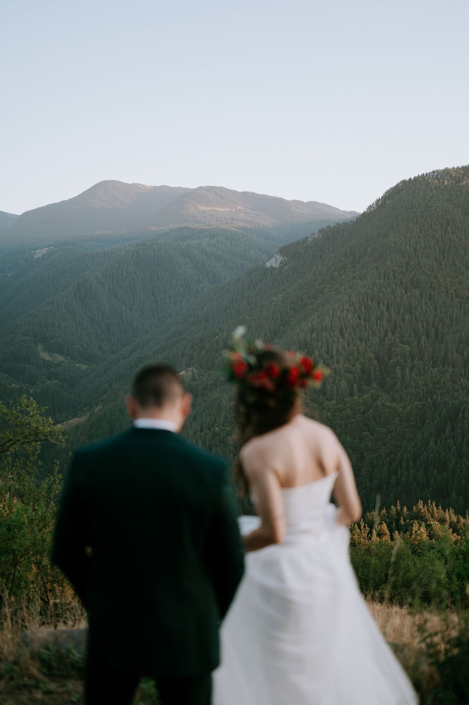 A wedding couple silhouetted against a stunning mountain landscape view.