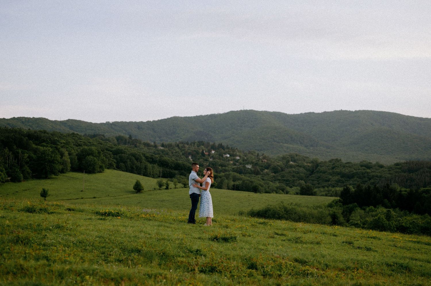 Pastoral mountain scene with tent and people enjoying the green hillside vista.