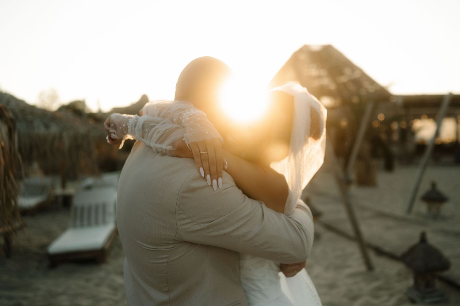 Silhouetted couple embraces in a warm sunset glow with palm trees in the background.