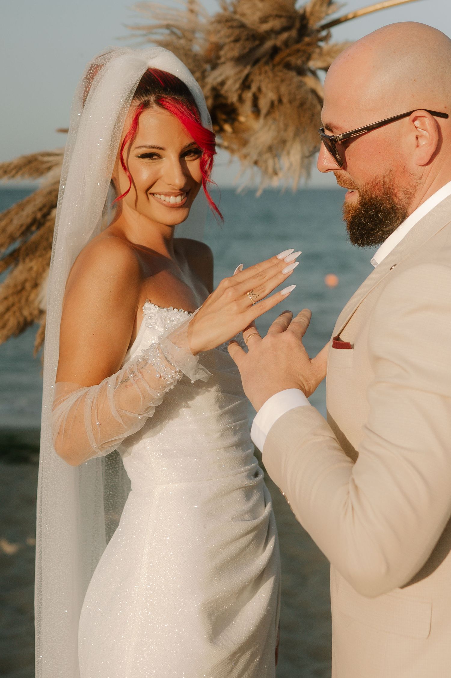 A romantic beach wedding scene shows a couple in white sharing tender moments against an ocean backdrop at sunset.