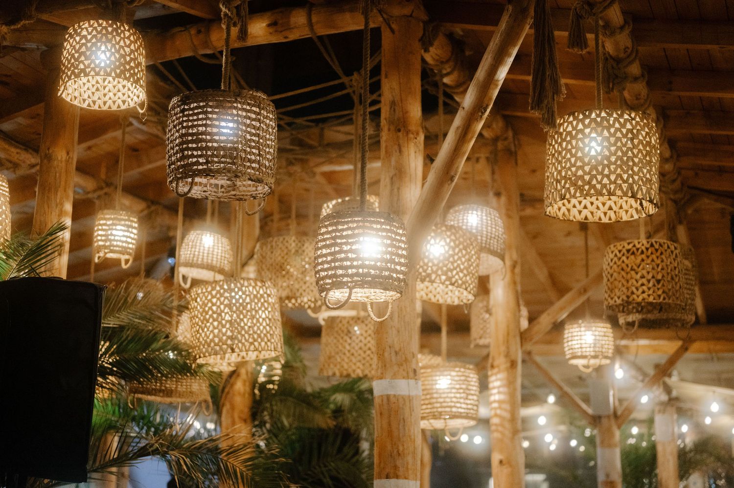 Crystal chandeliers and warm lighting create an elegant ambiance in a rustic wooden beam ceiling venue.
