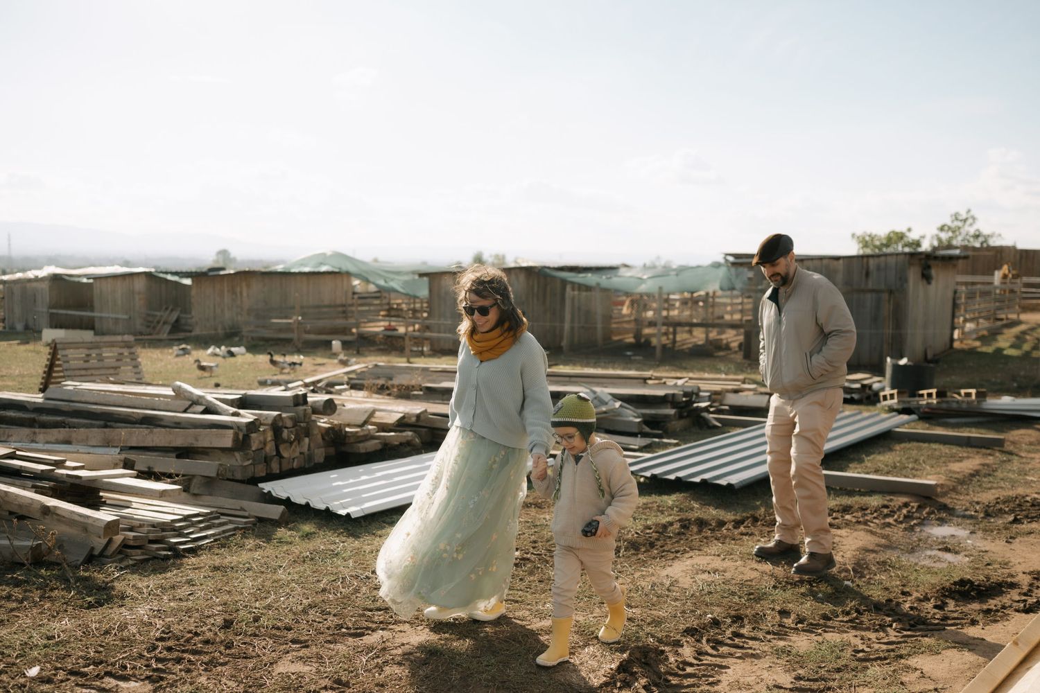 A couple in wedding attire walks through a desolate, post-disaster landscape with debris and rubble surrounding them.