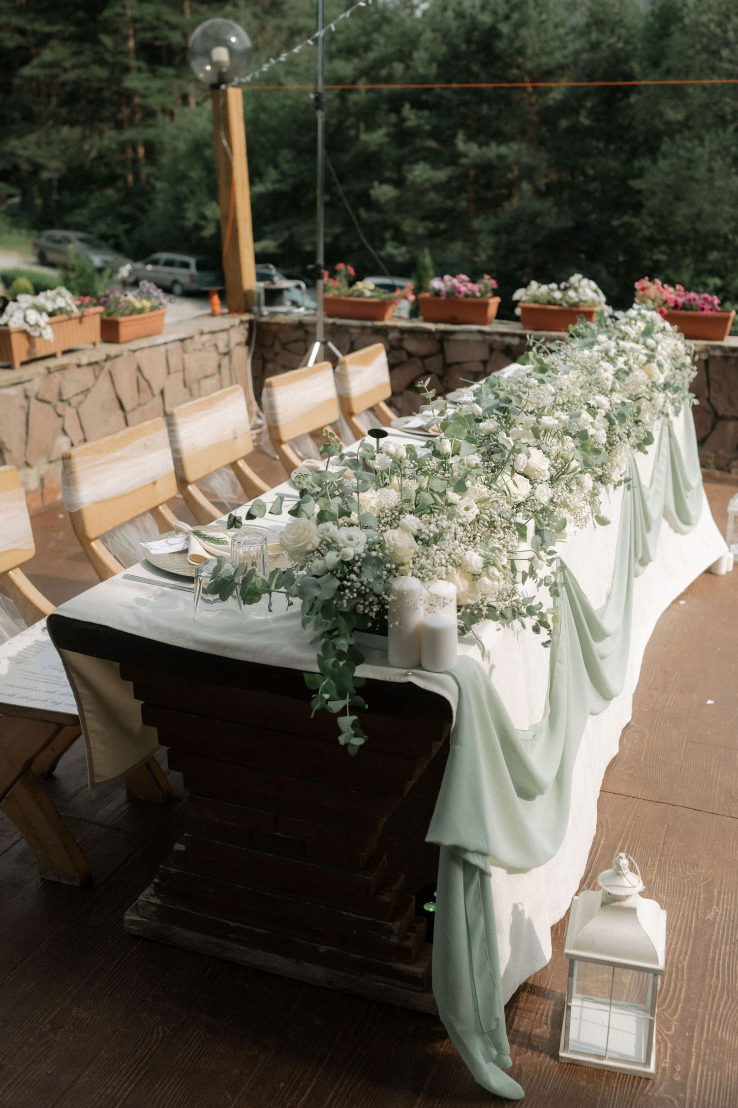 White floral arrangements with eucalyptus decorate wooden church pews for a wedding ceremony.